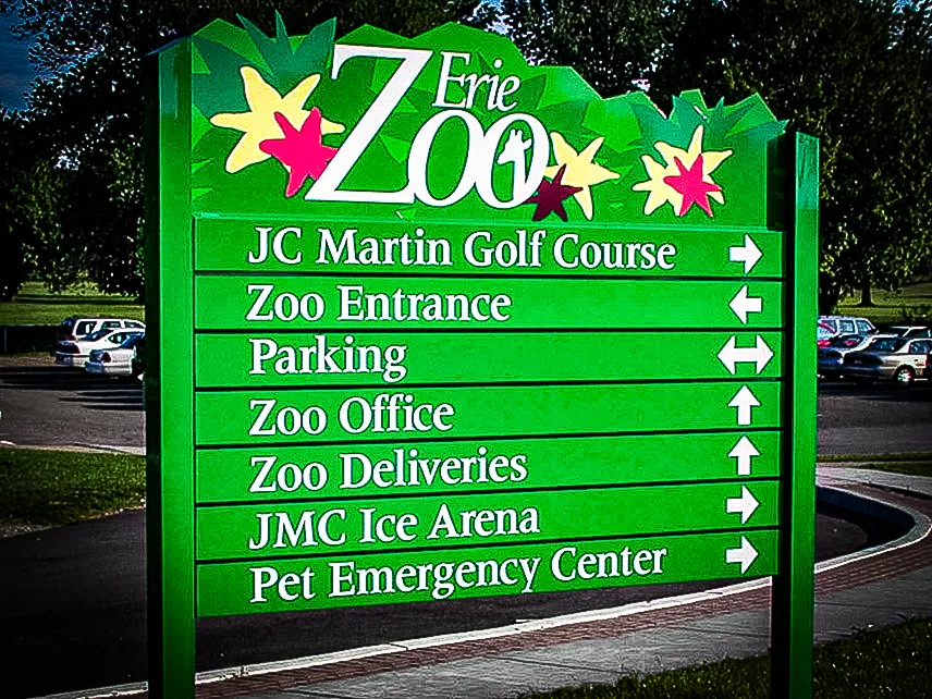 Commercial exterior sign with green awnings directing visitors at Erie Zoo