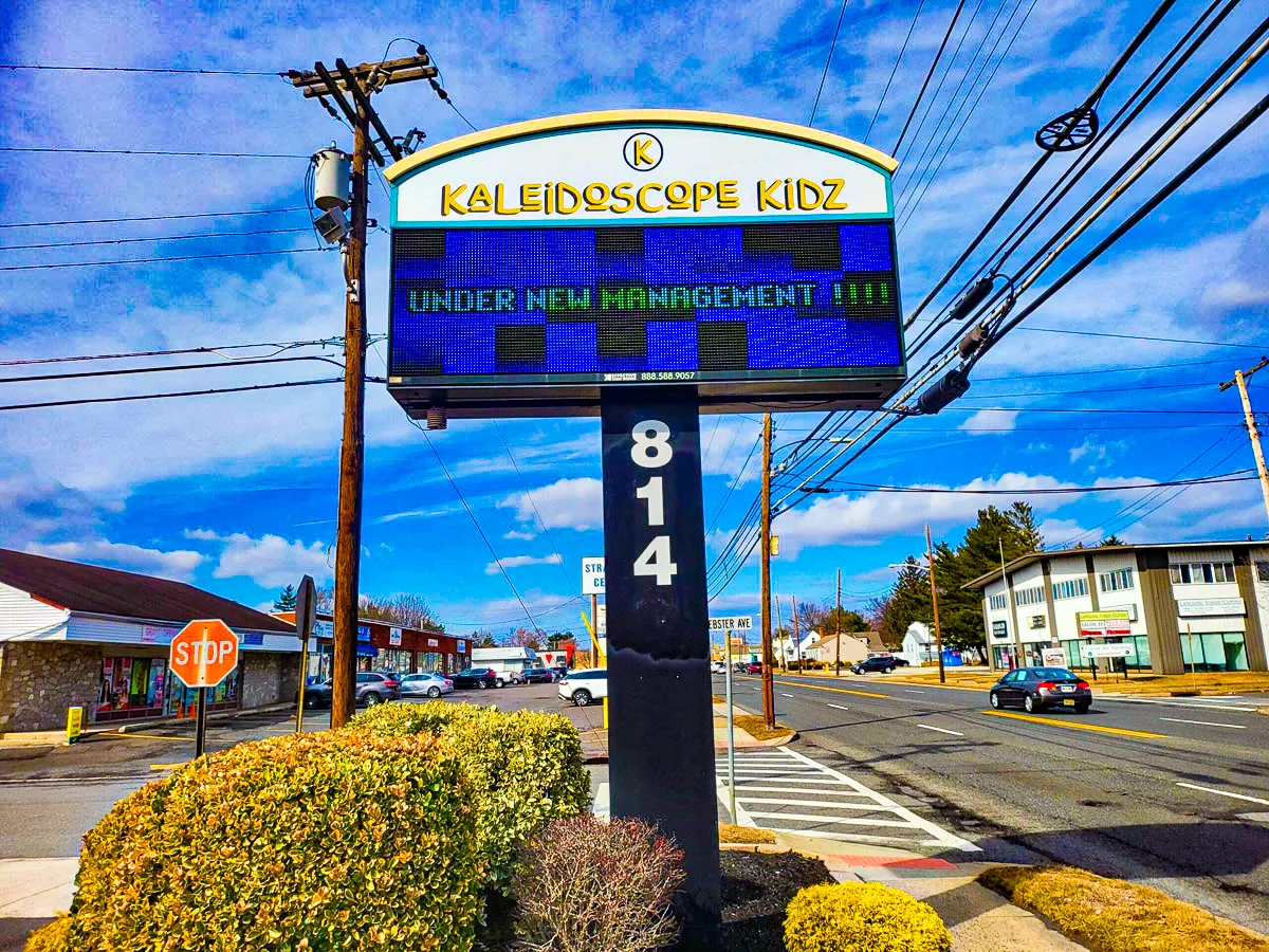 Commercial exterior with Kaleidoscope Kidz signs, awnings, and roadside landscape