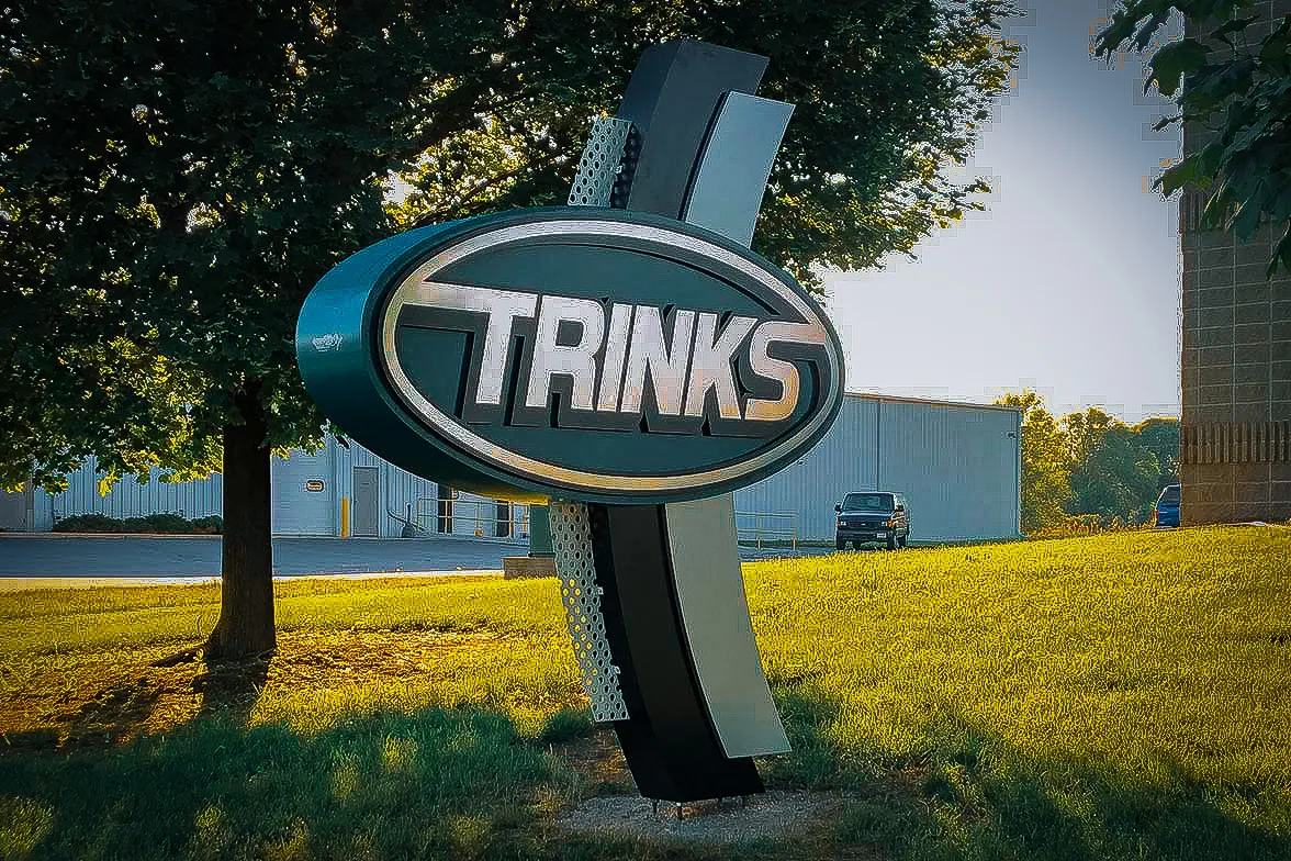 Commercial exterior sign for Trinks with industrial building and trees