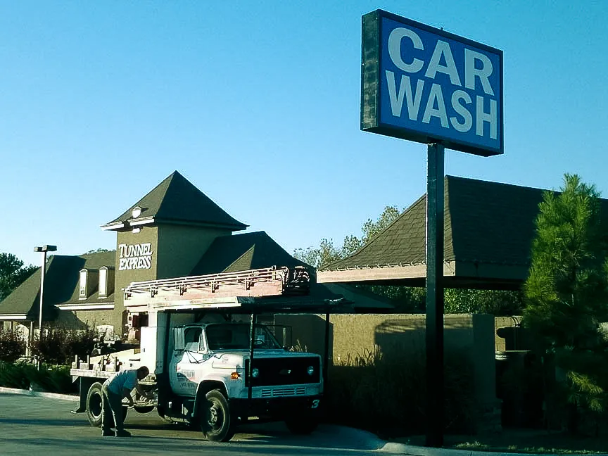 Commercial exterior car wash with signs, awnings, and shades near truck