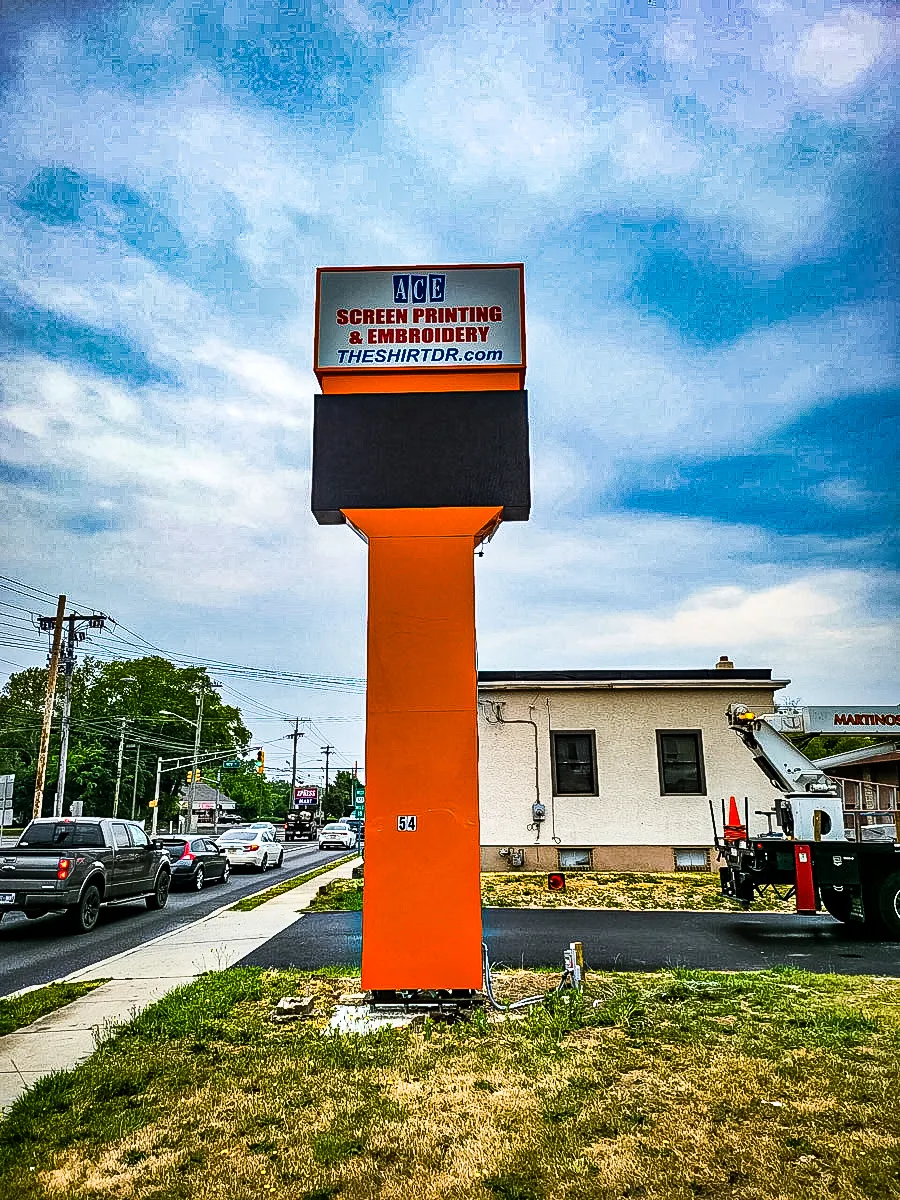 Commercial exterior sign for ACE Screen Printing with vibrant orange awnings