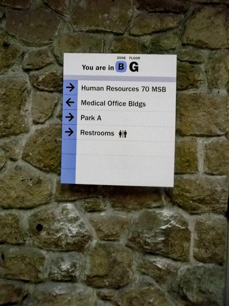 Commercial interior signs on stone wall for building zone B-G, showing directions