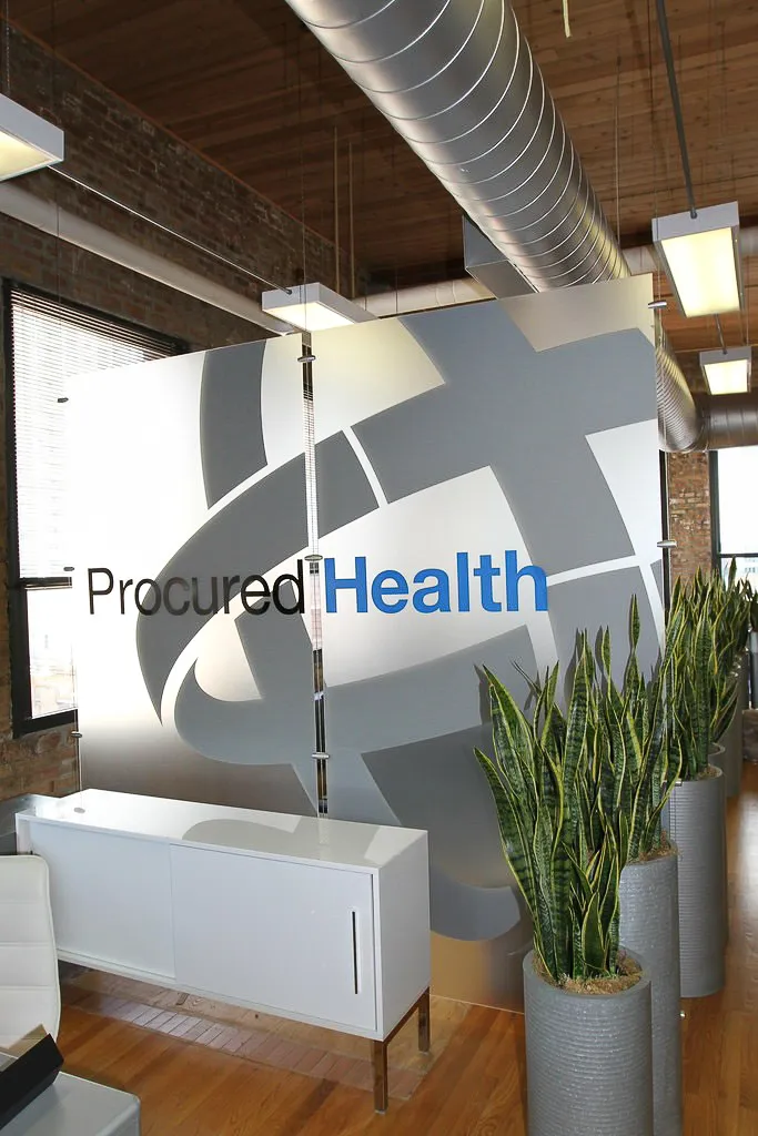 Commercial interior with Procured Health signs, exposed ducts, and modern shades