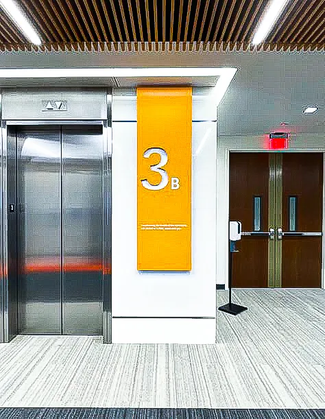 Commercial interior with elevator, exterior signs, yellow awning, and shades