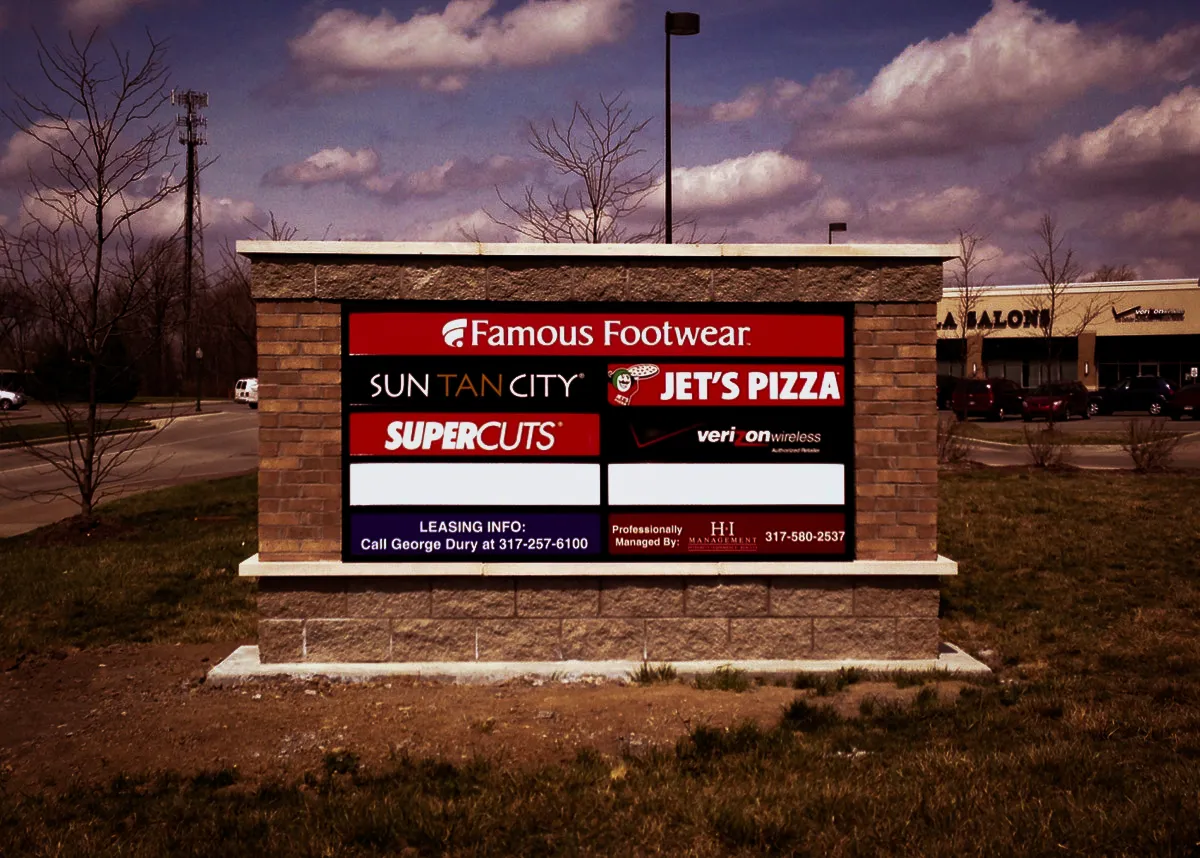 Commercial exterior sign with business logos, awnings, and leasing information