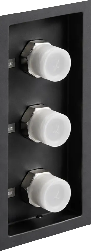 Close-up of three white plastic caps attached to hexagonal metal fittings on a black panel.