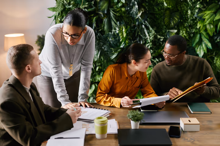 Quatre personnes discutent autour d'une table lors d'une réunion. Cabinet de conseils stratégie, marketing et développement commercial