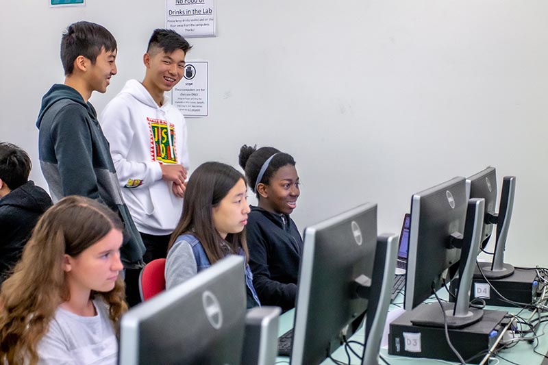 A group of stuents in the calss studying on the computers.