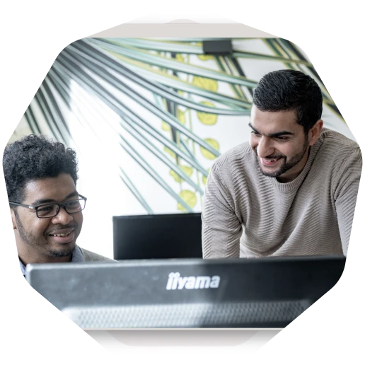 Two men sitting in front of a laptop computer.