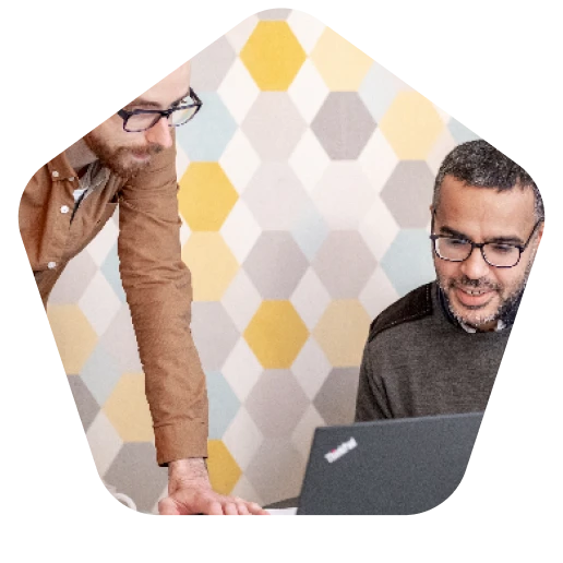 Two men are looking at a laptop computer.