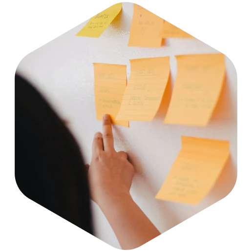 A person pointing to sticky notes on a wall.
