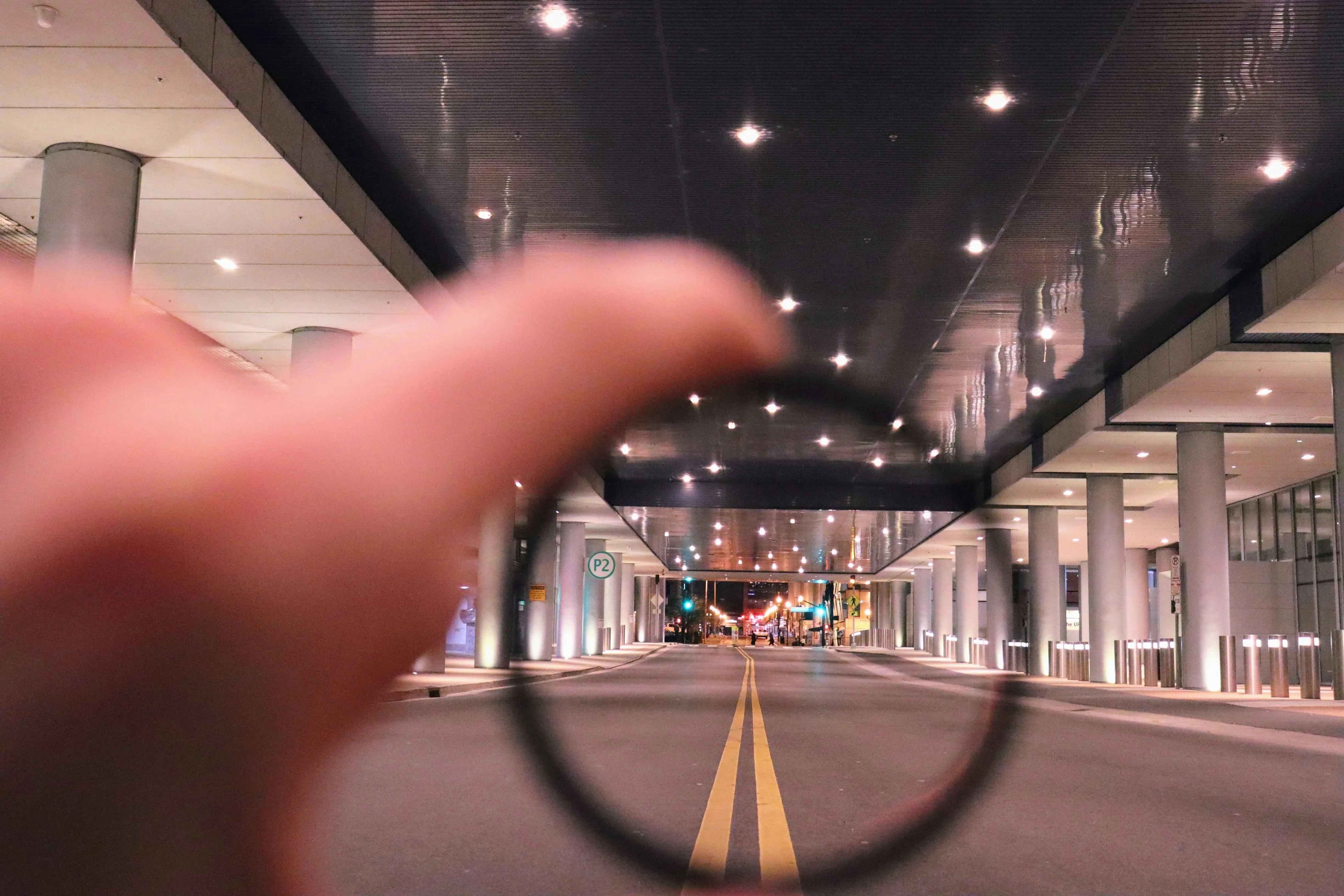A hand holding a magnifying glass over a street.