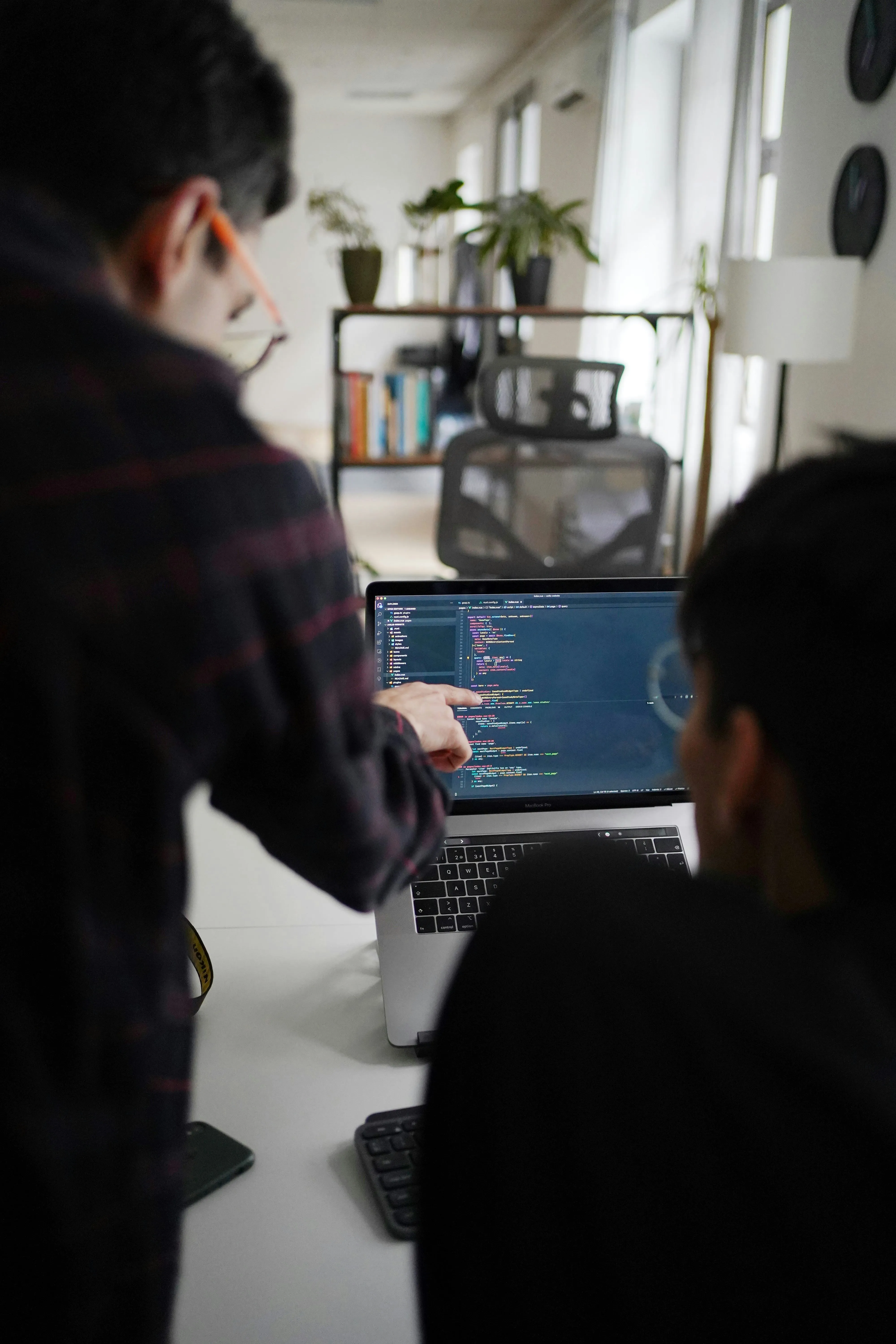 Two men sitting at a table with laptops.