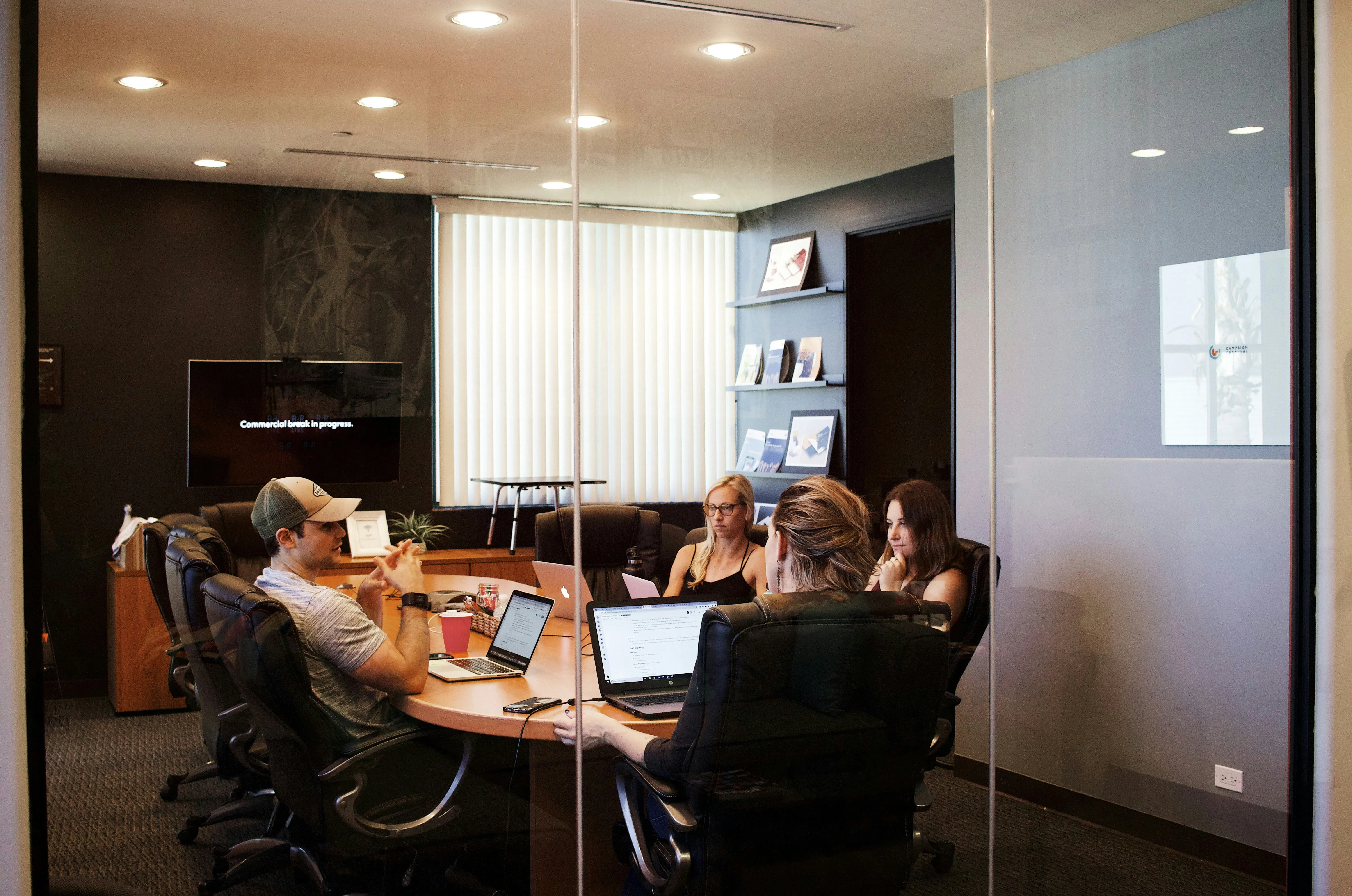 A group of people sitting around a table with laptops.