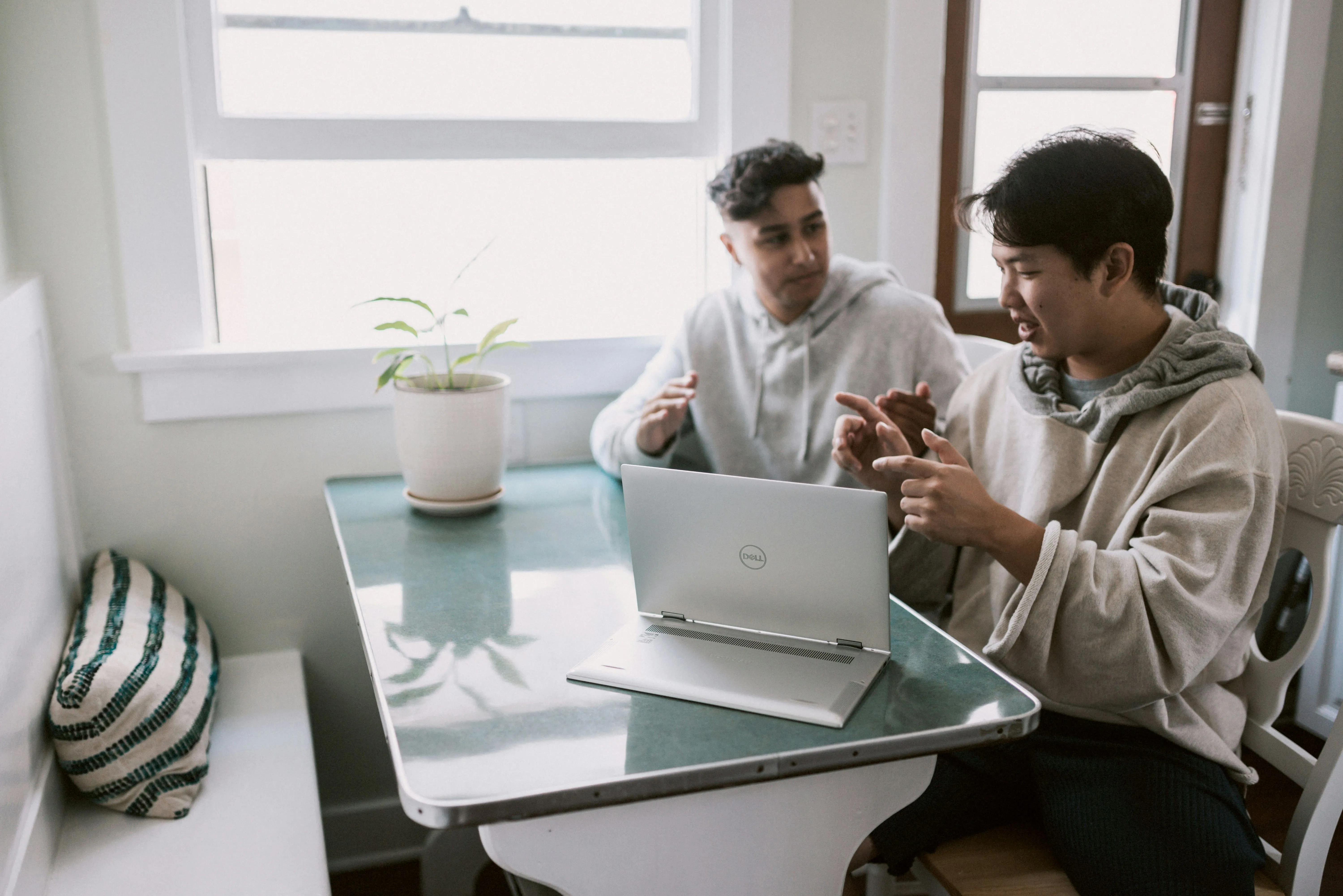 Two men sitting at a table looking at a laptop.