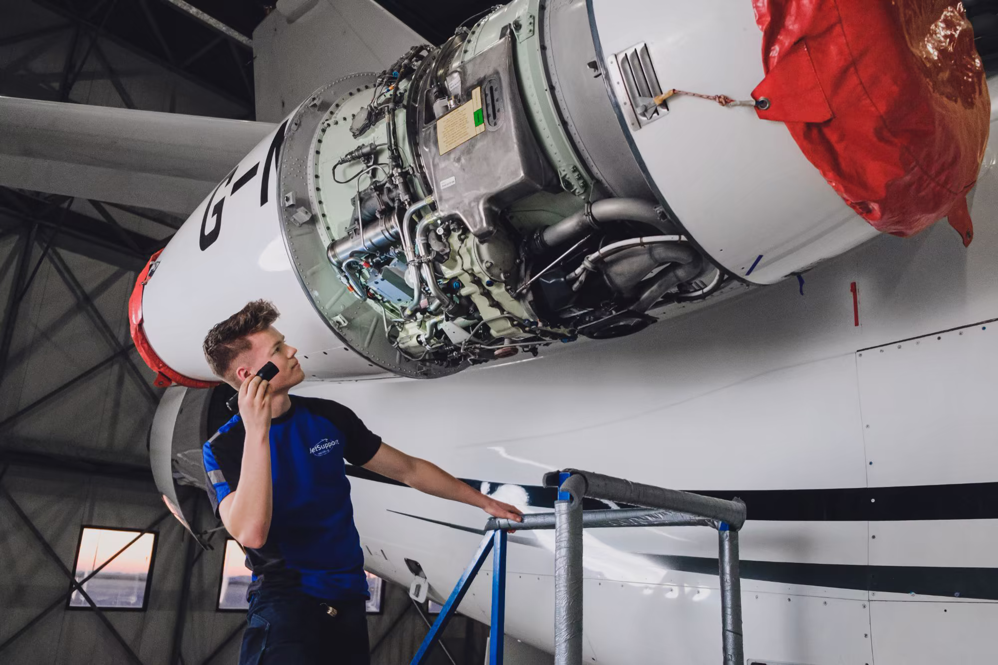 Technician on the phone under an opened engine