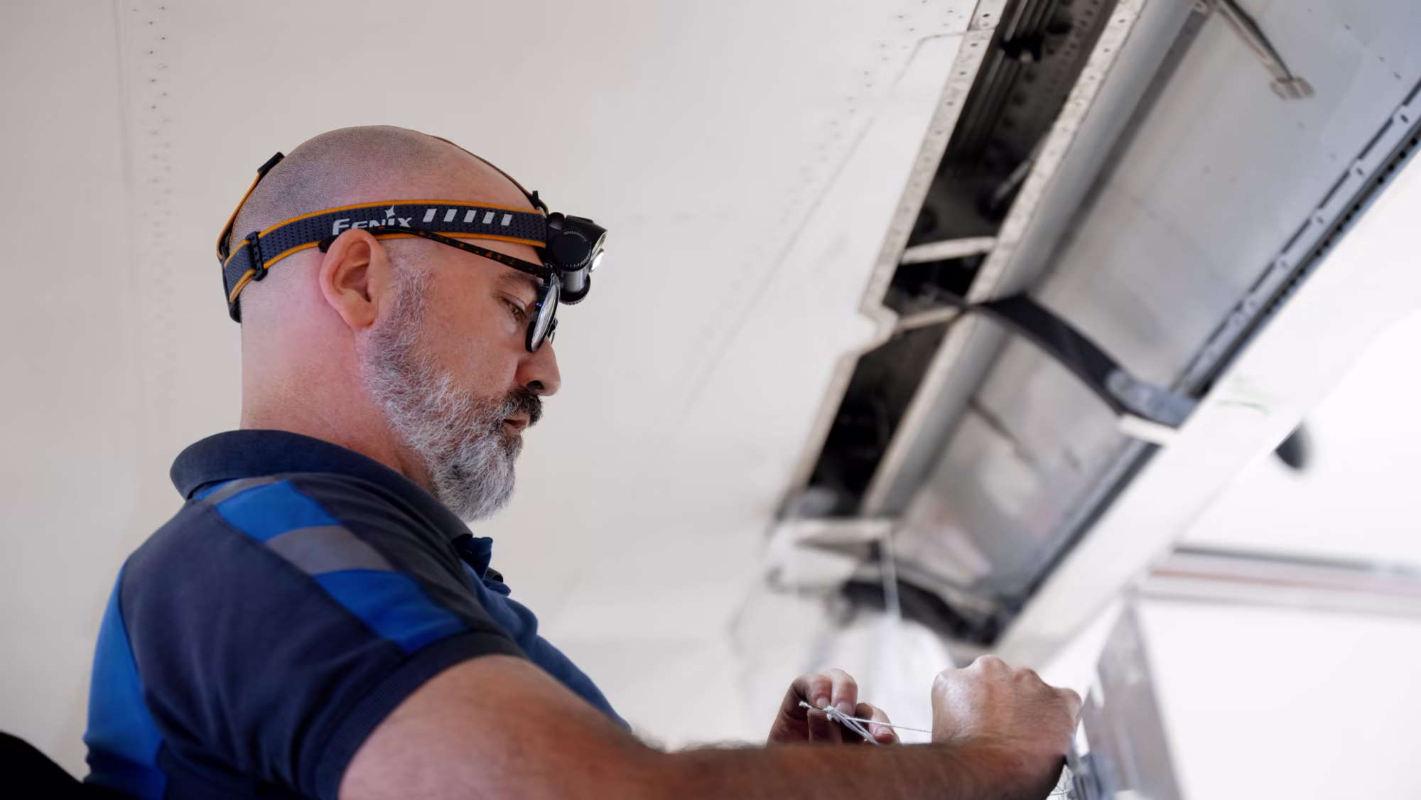 Engineer with a head torch inspecting a wing panel