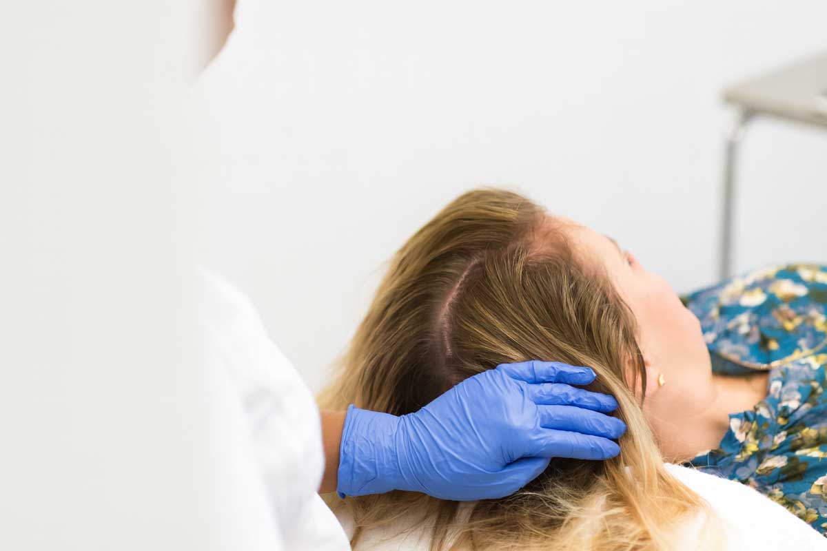 En kvinna får sitt hår undersökt