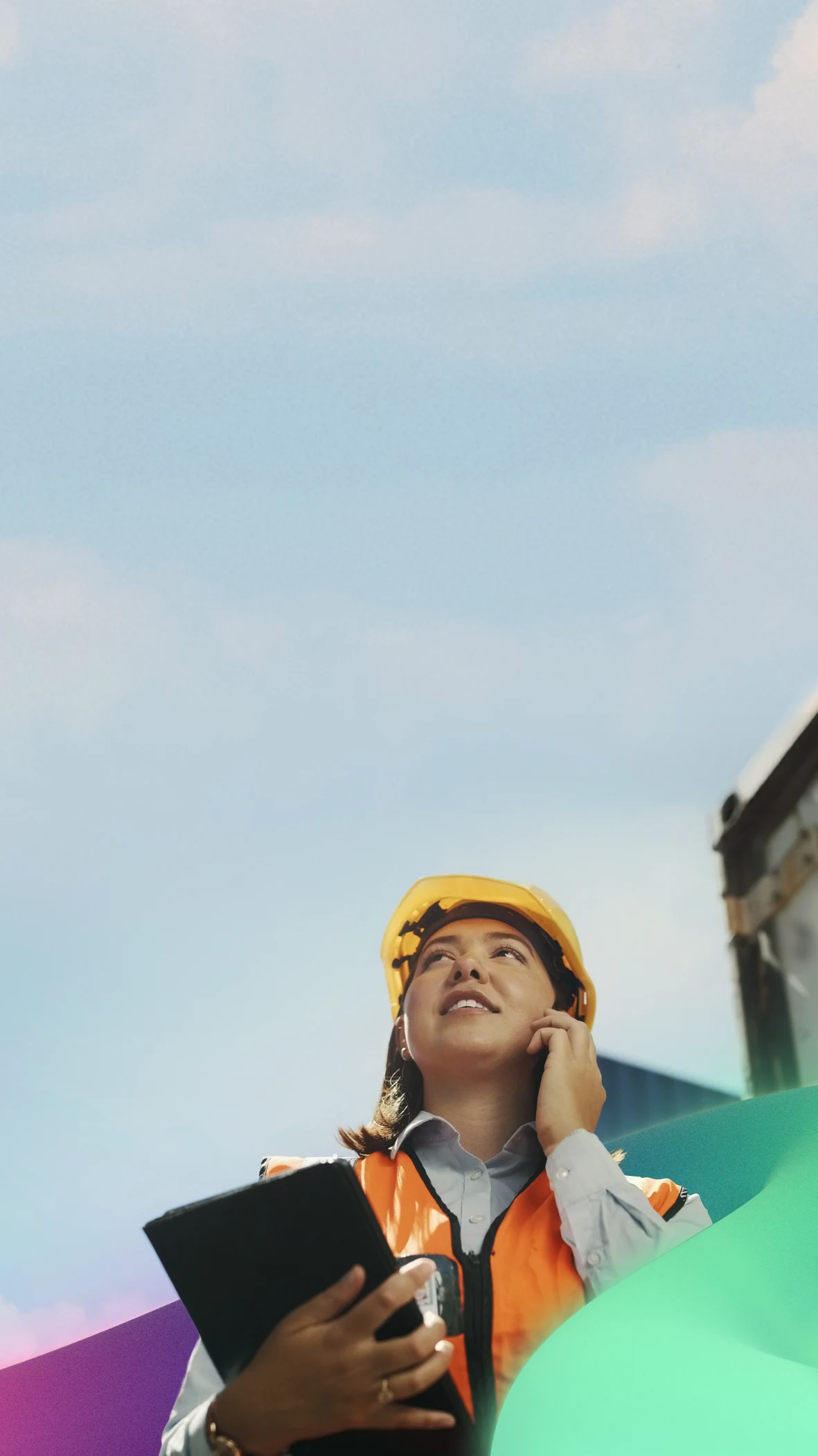 Construction worker in yellow hard hat looking up with clipboard