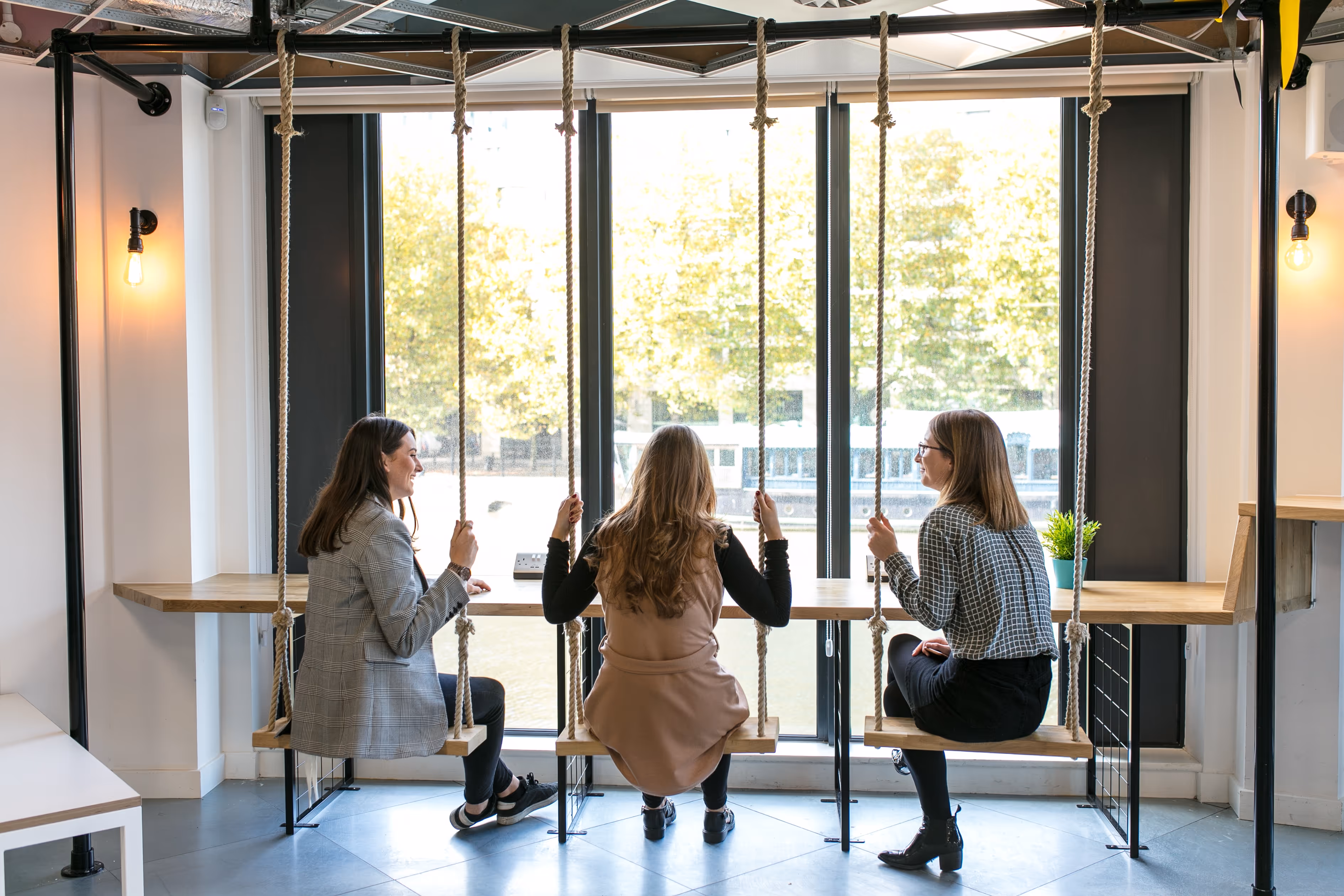 Three women hanging from swings at coworking space Runway East Bristol Bridge