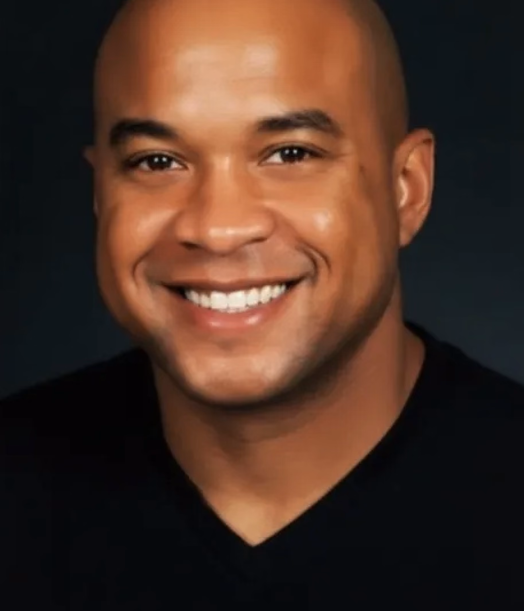 Smiling bald man with a dark shirt against a black background.