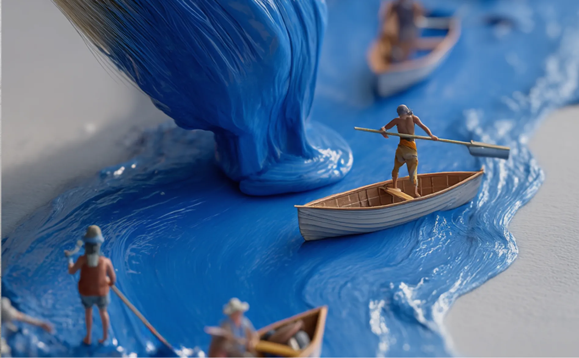 Miniature rowers navigating small boats through a flowing stream of thick blue paint.