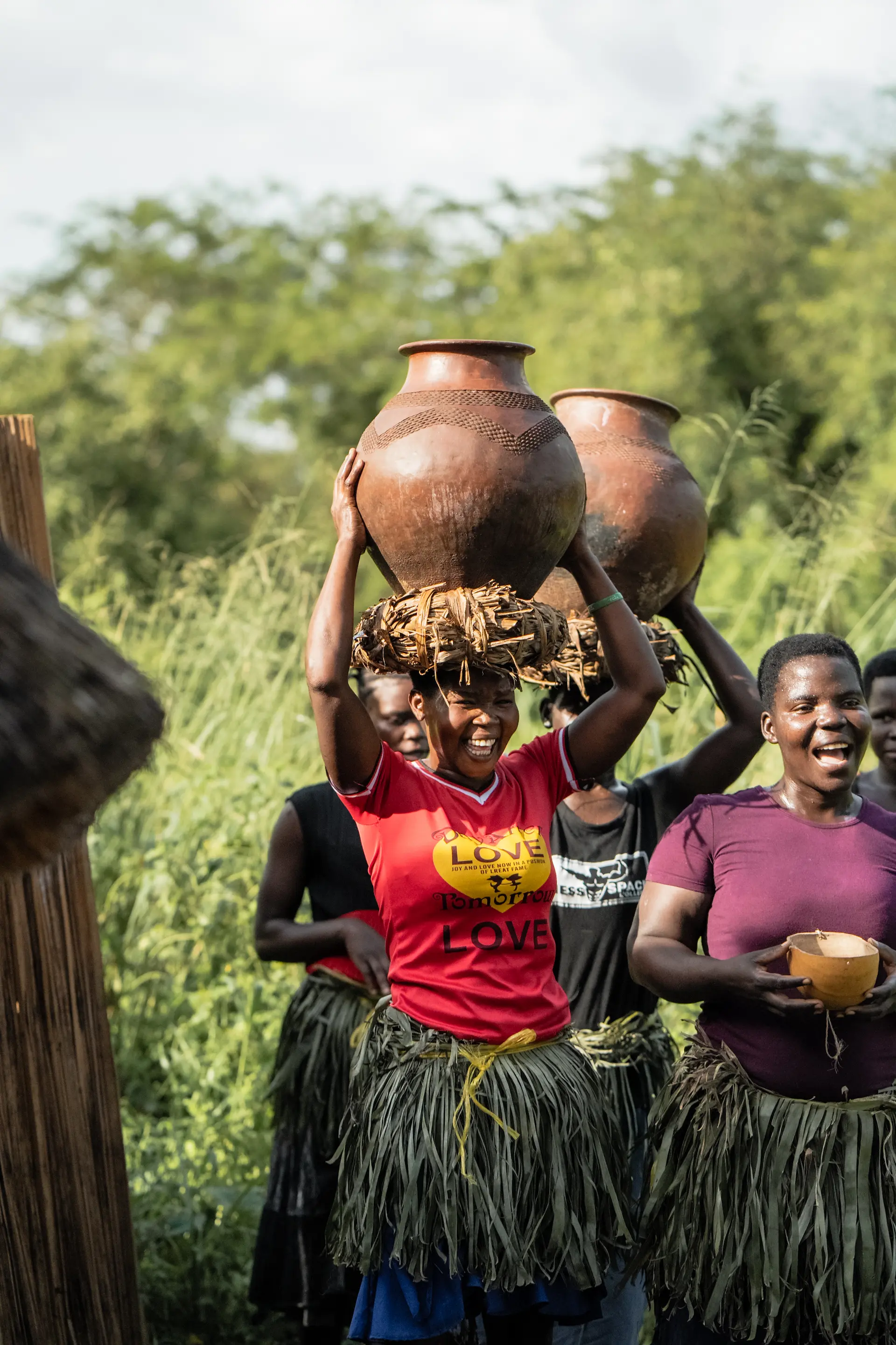 Ugandan women carrying water in large clay pots 