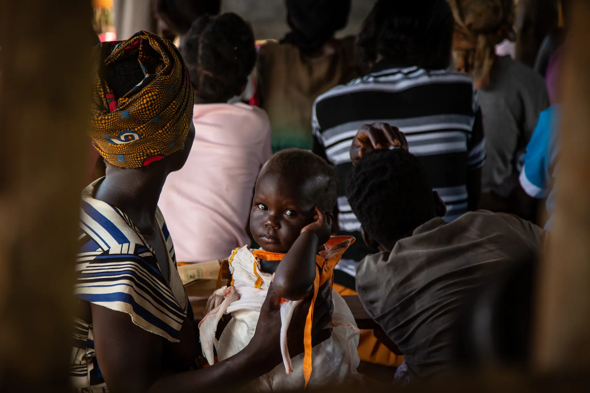 Ugandan mother and her child attending a community classroom 