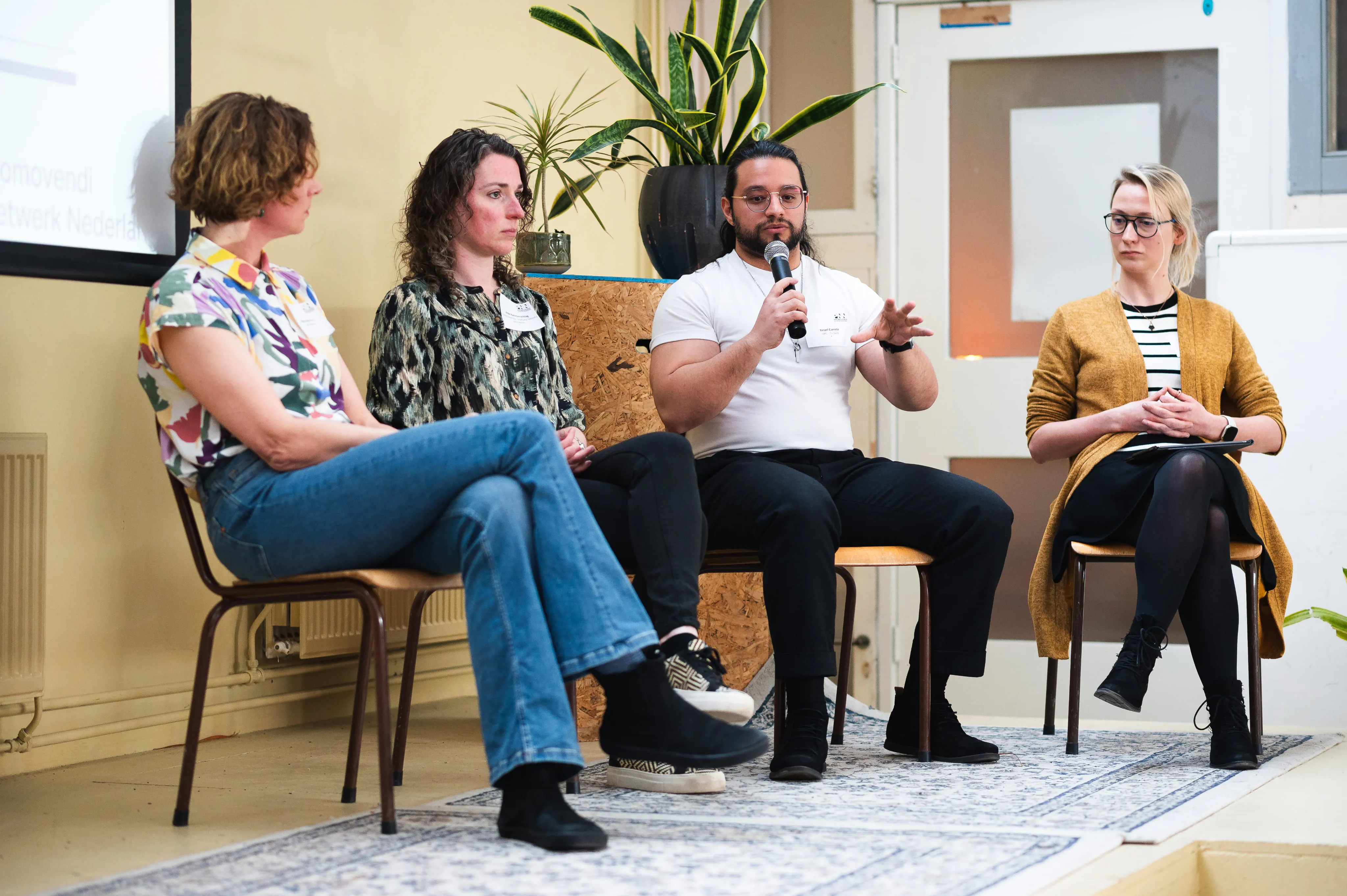Four people seated in panel discussion, one speaking into microphone