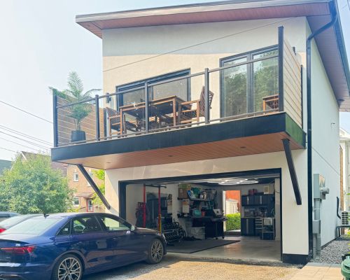 Two-storey coach house with a garage below and a finished income suite above opening onto a balcony