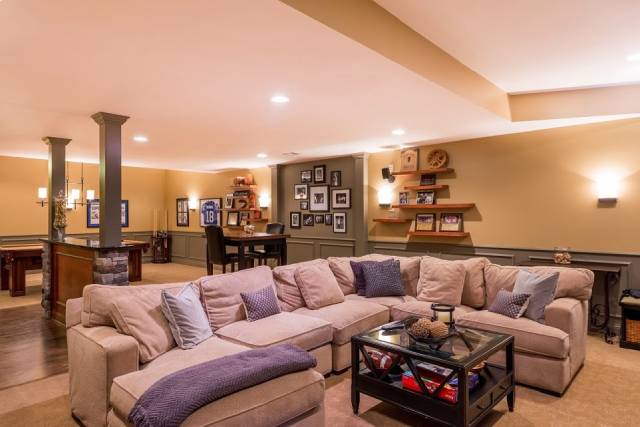 Finished basement living space with pot lights and neutral finishes