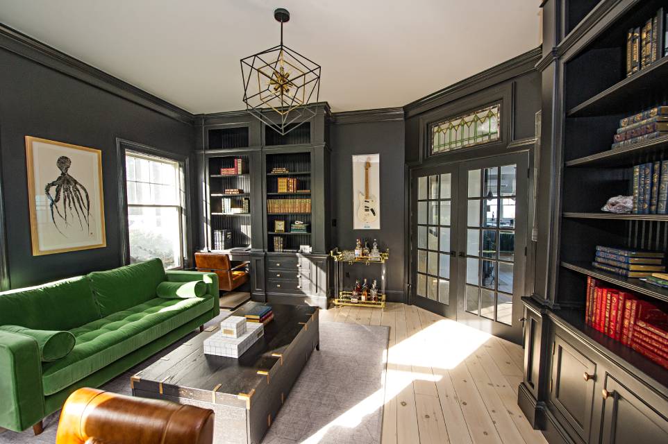 Home office with built-in bookshelves, a green sofa, and French doors