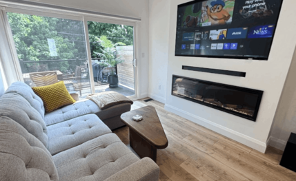 Living room with a linear fireplace, a media wall, and sliding doors to the yard