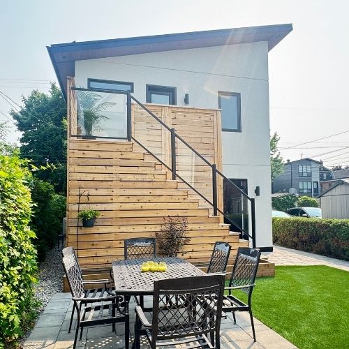 Two-storey detached income suite with cedar siding, an exterior stair, and a separate tenant entrance