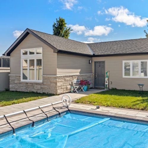 Single-storey home addition beside a pool, with siding and stone