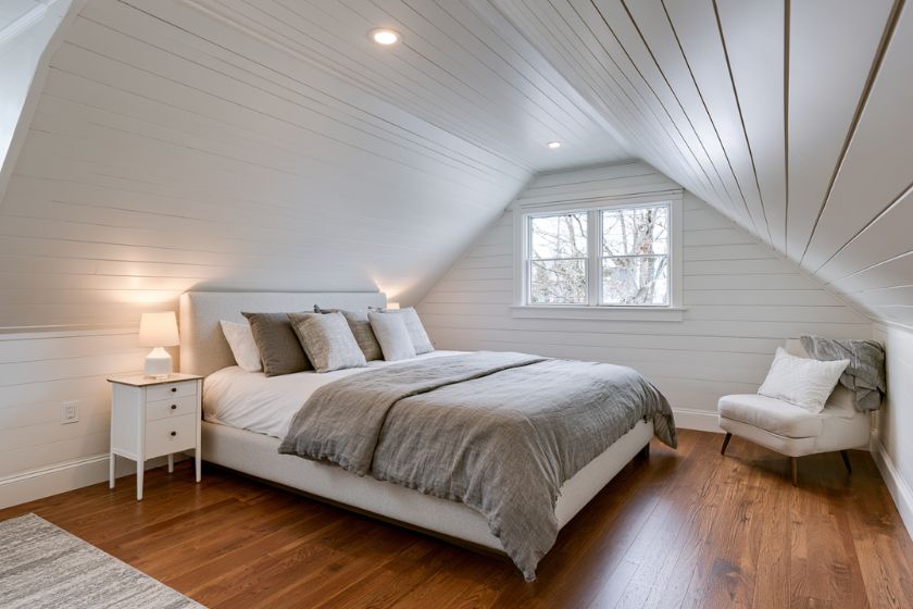 Attic suite bedroom with a white shiplap vaulted ceiling and hardwood floor