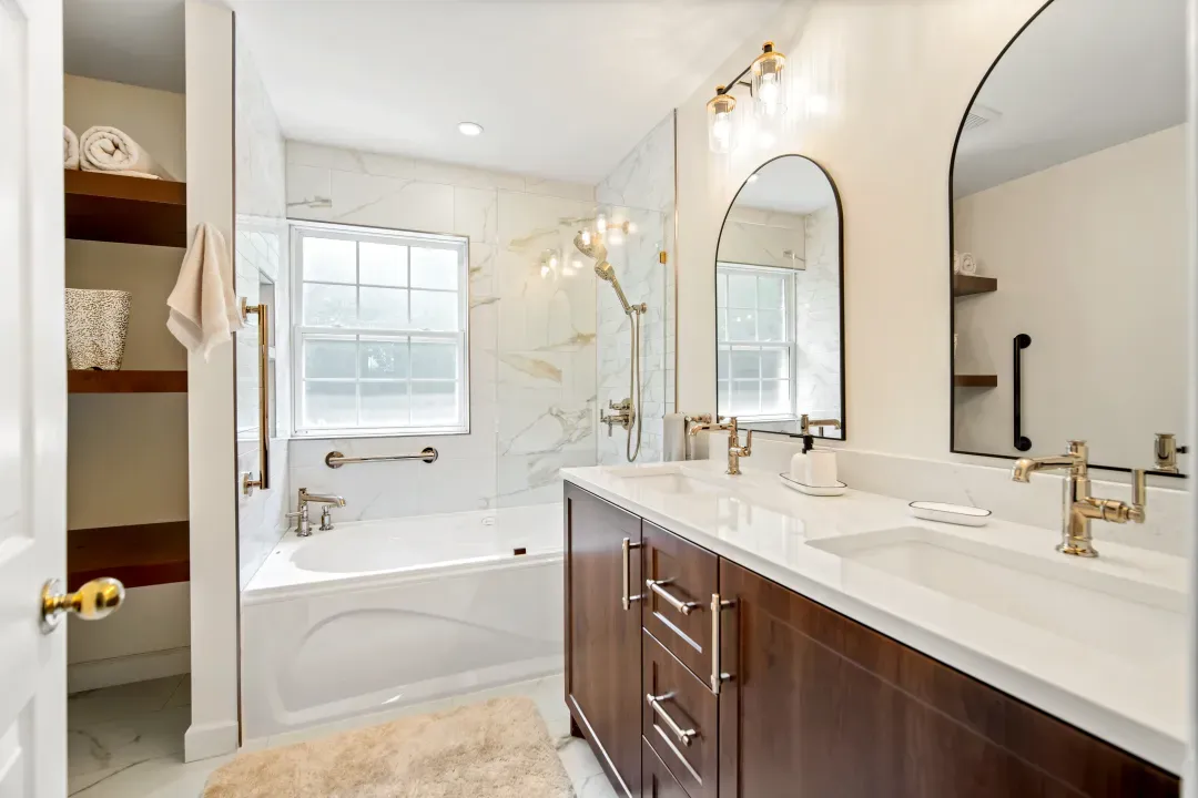 Bedford ensuite with dark wood vanity, white quartz, gold fixtures and arched mirror