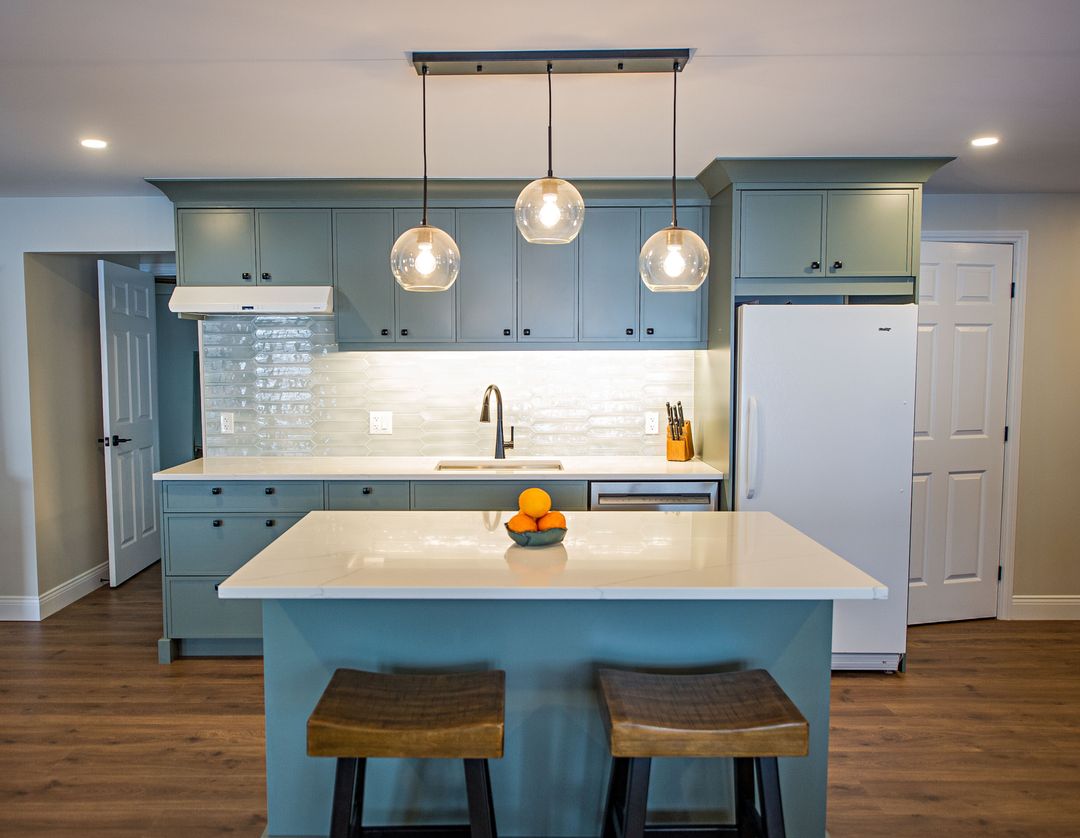 Lake Echo basement kitchenette with teal cabinets, white island and pendant lights