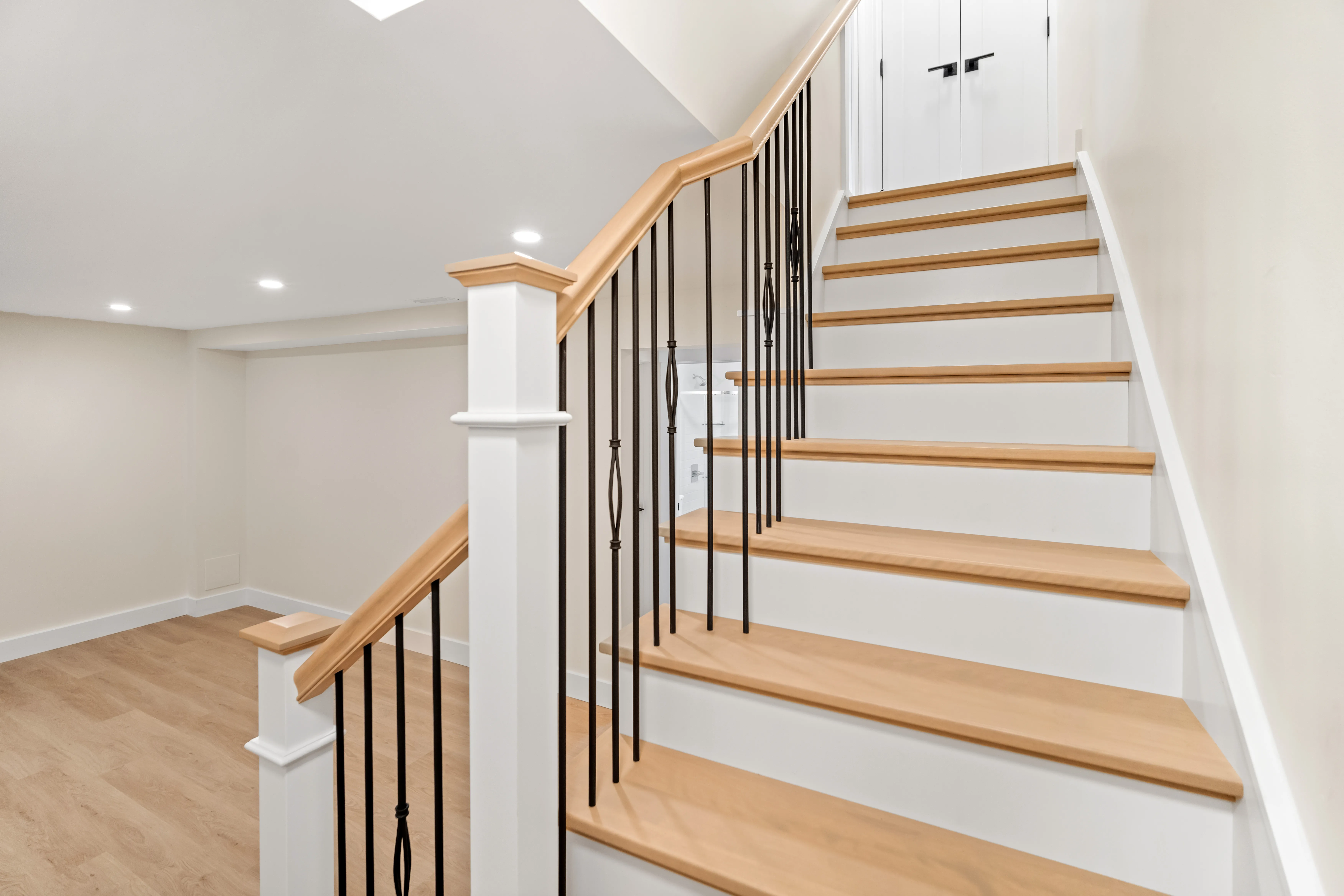 Timberlea basement with a rebuilt oak and white staircase with black iron balusters