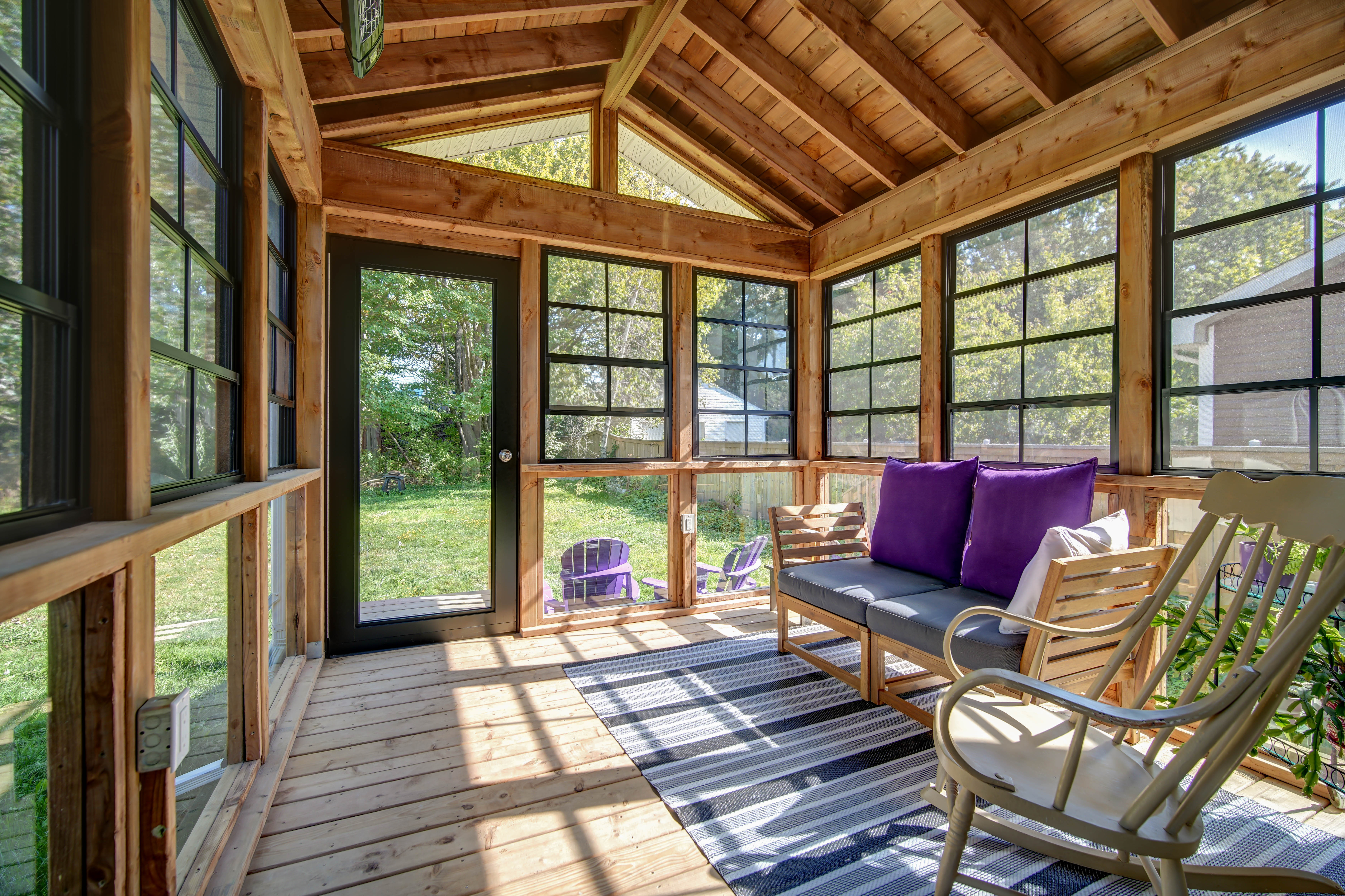 Interior of a Dartmouth addition with exposed stained timber trusses, a tongue and groove ceiling and black-framed windows on three sides