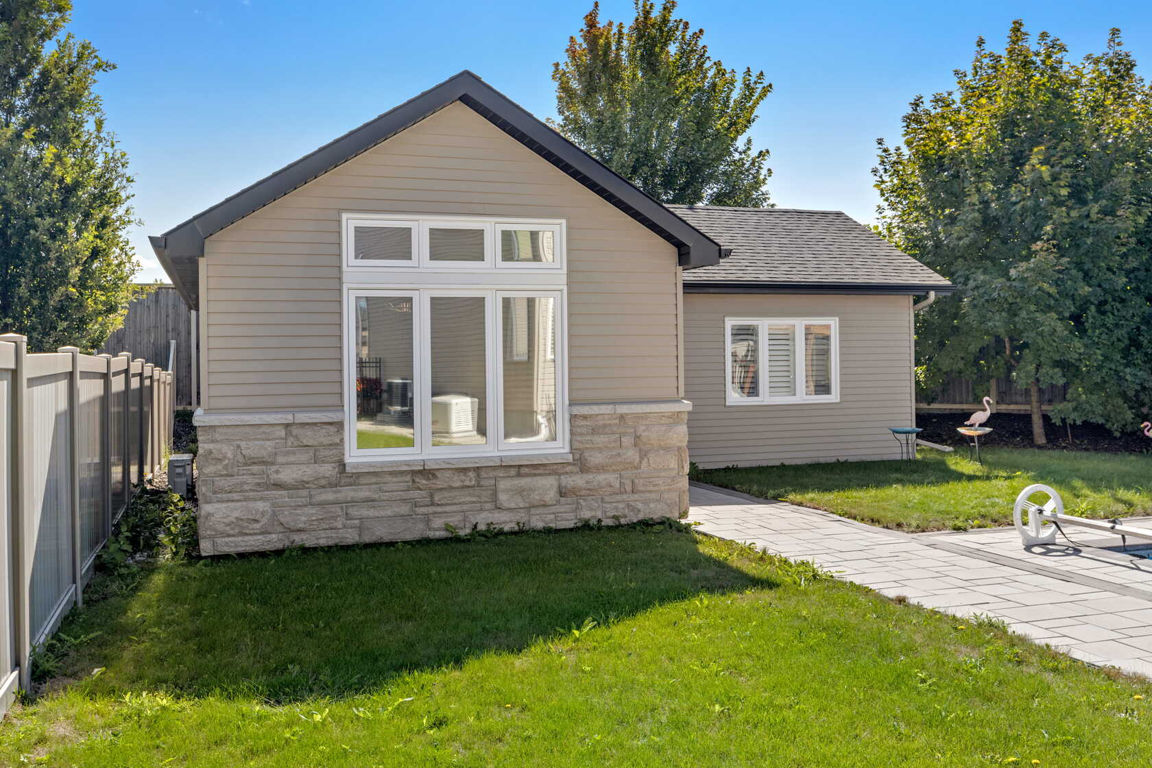 Single-storey detached backyard suite with stone base and large windows