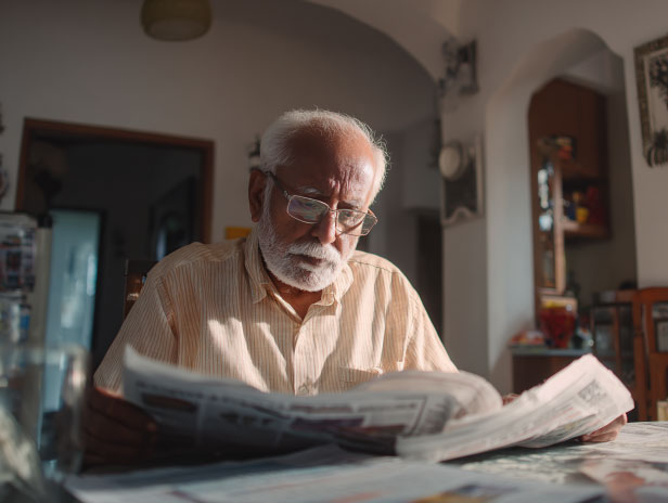 Old indian man reading newspaper with anxiety 