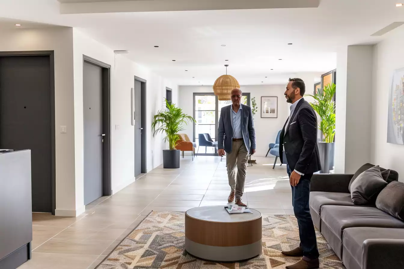 2 hommes se rencontrent dans le hall d'une residence services