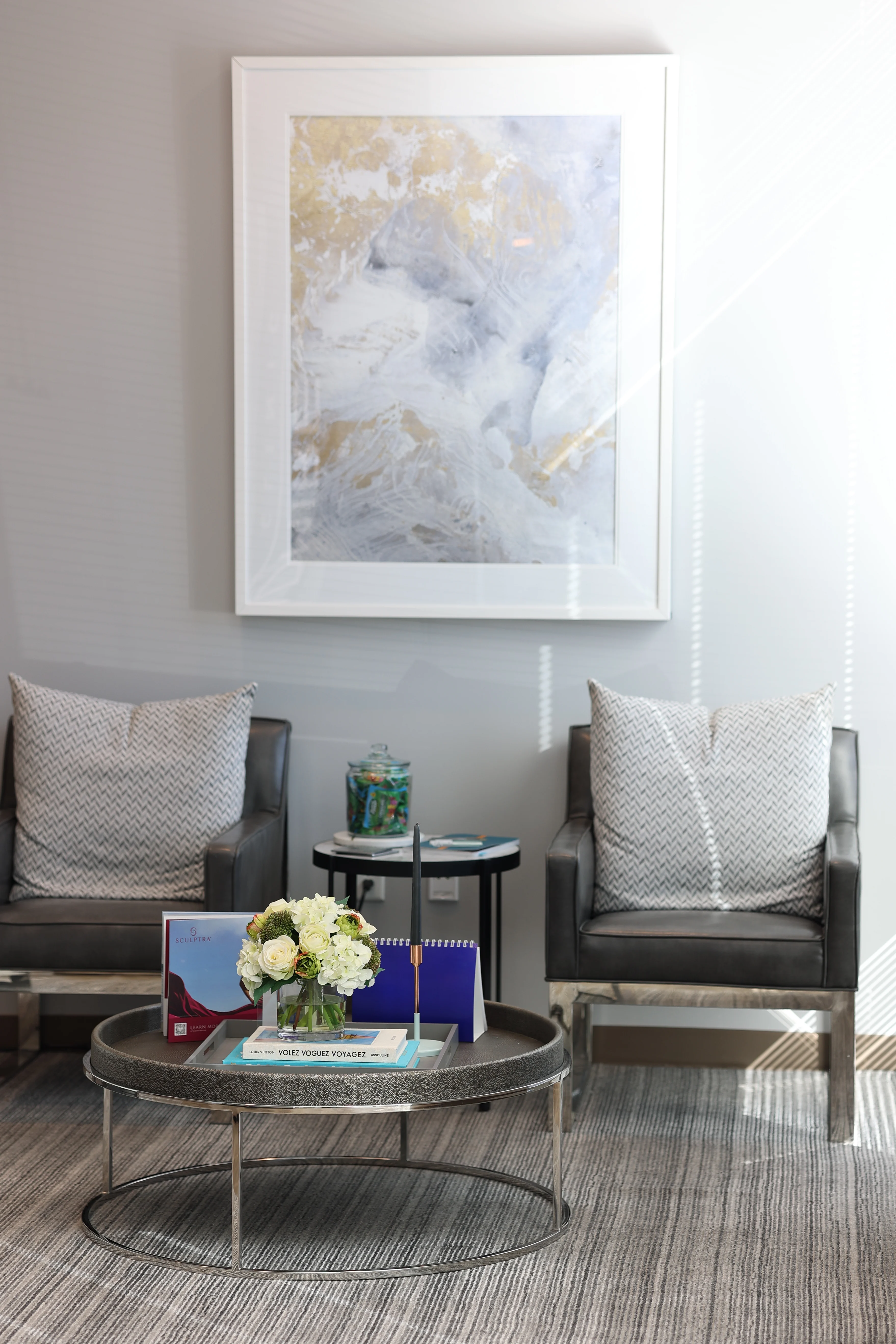 Waiting area in Scottsdale office of Metropolitan Plastic Surgery with gray leather chairs, contemporary art, and a coffee table with floral arrangement.