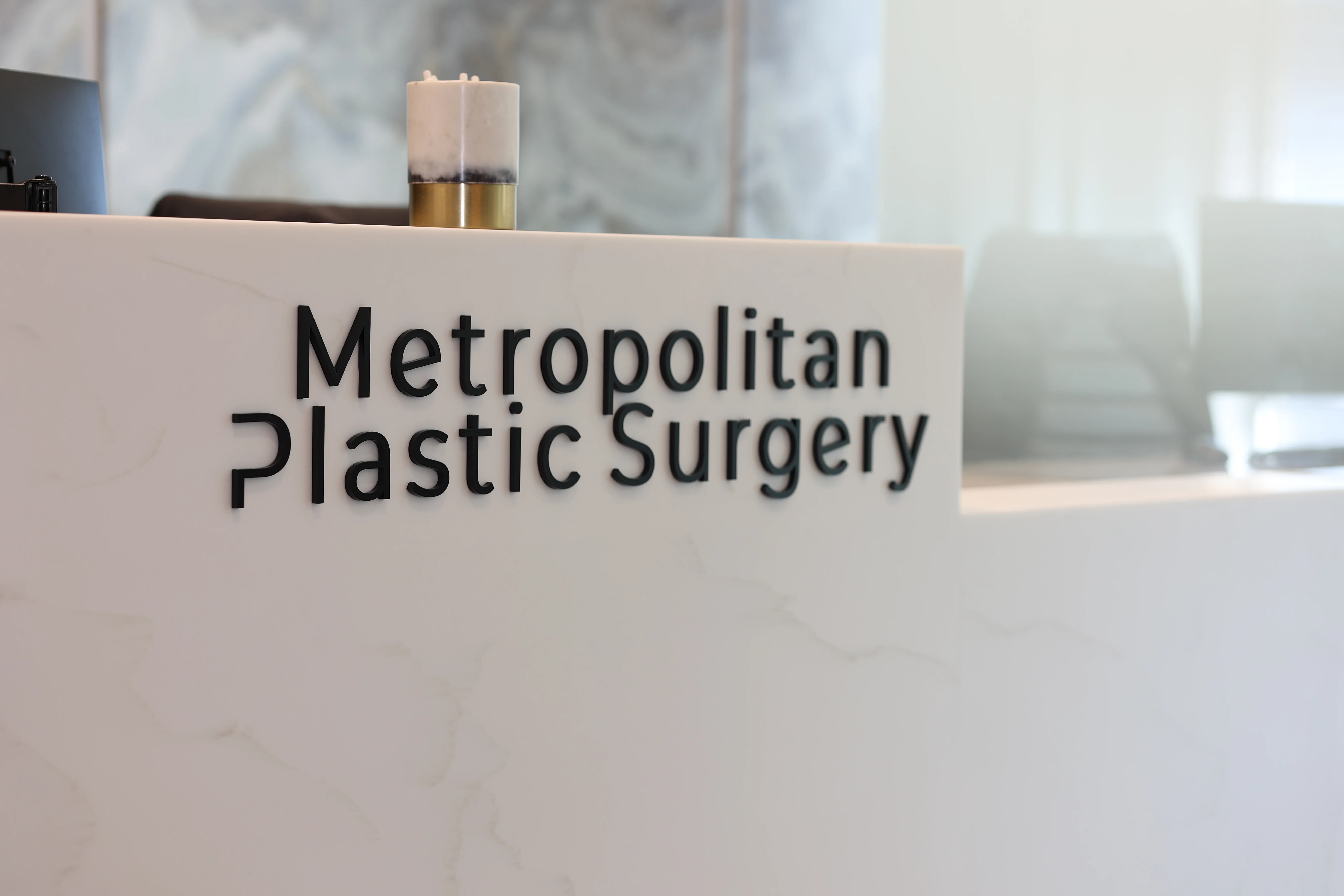 Reception desk with Metropolitan Plastic Surgery logo in Scottsdale Arizona office, featuring sleek marble design.