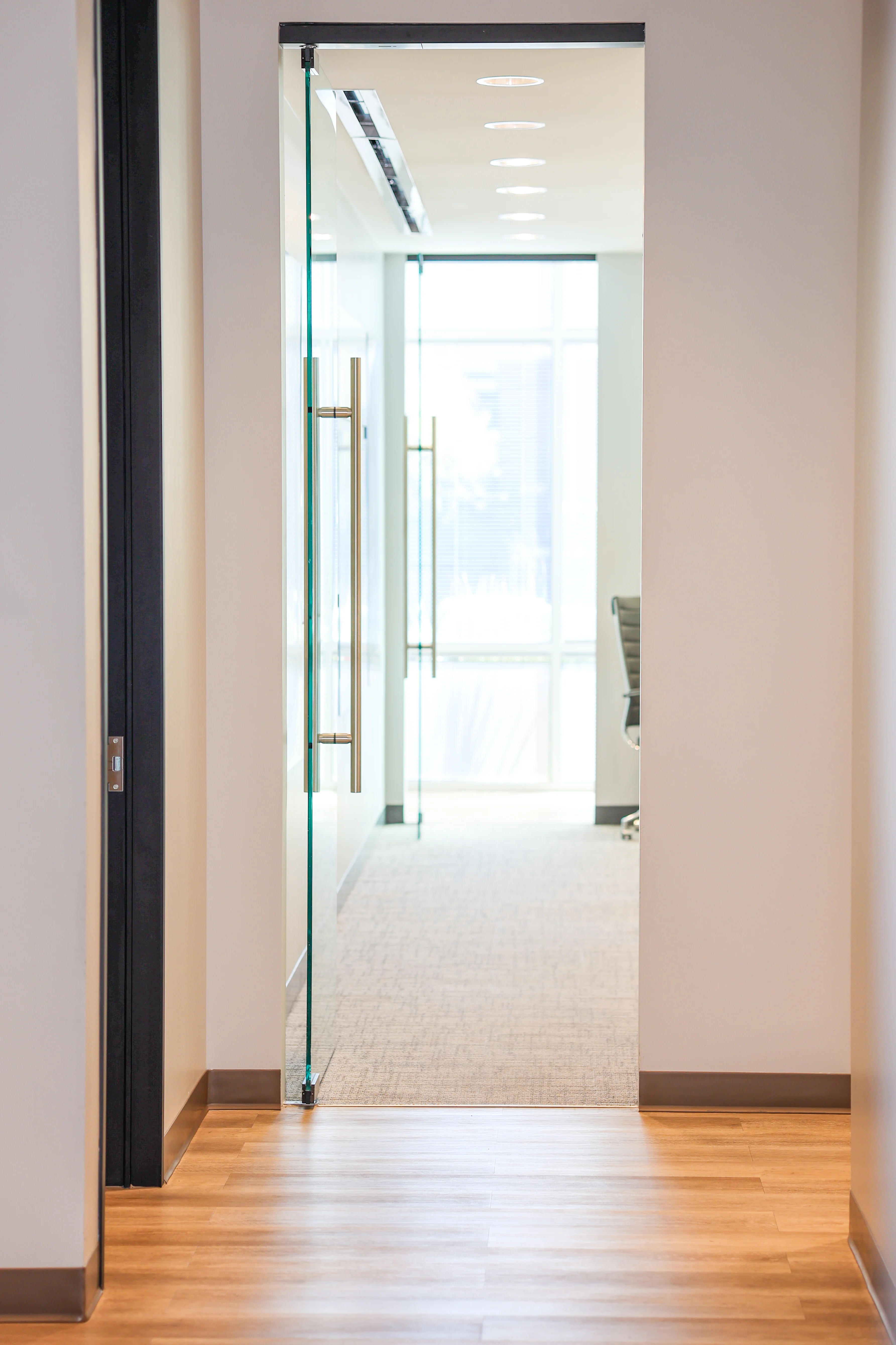 Glass doorway and hallway with sleek flooring and modern lighting at Metropolitan Plastic Surgery in Scottsdale, Arizona.