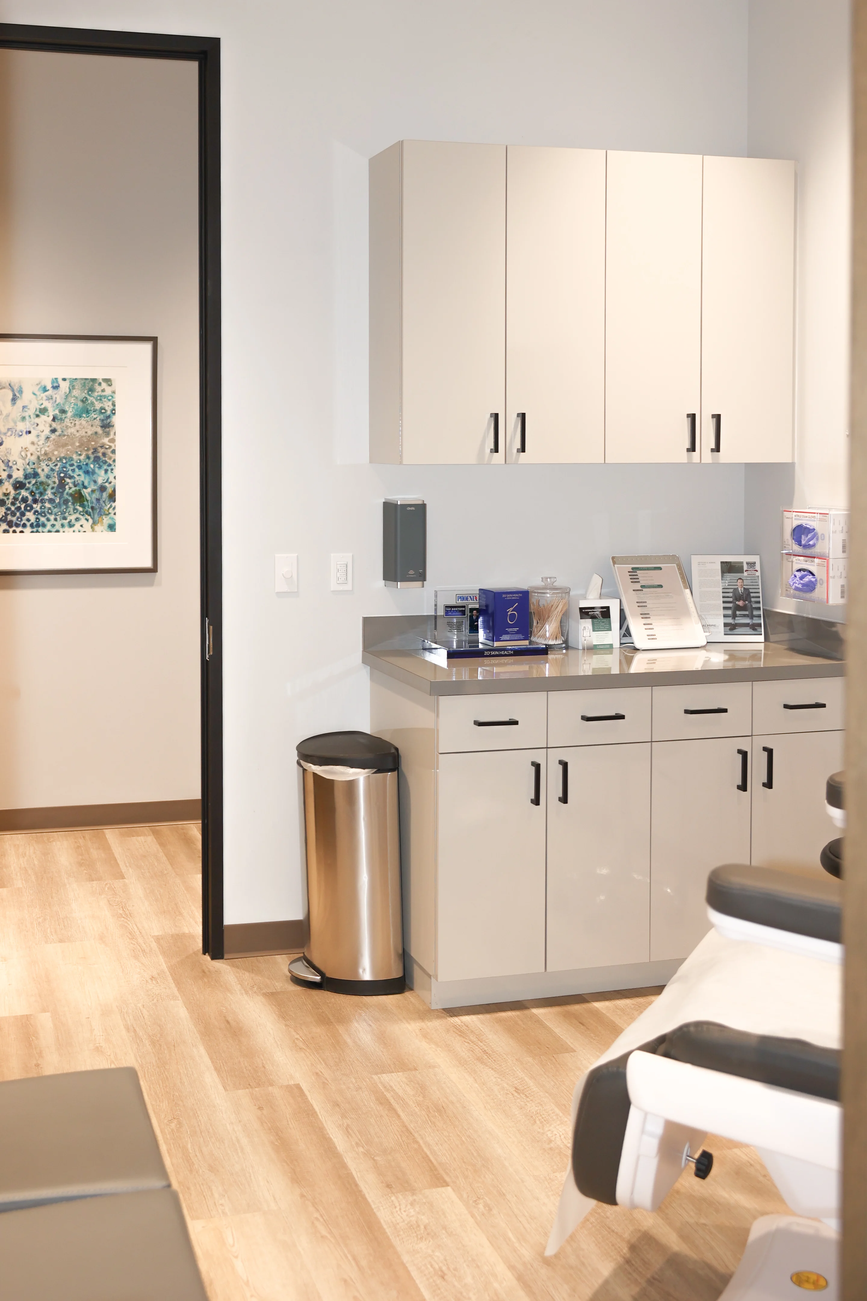 Medical exam room cabinetry and counter at Metropolitan Plastic Surgery Scottsdale office, with supplies and promotional materials neatly arranged.