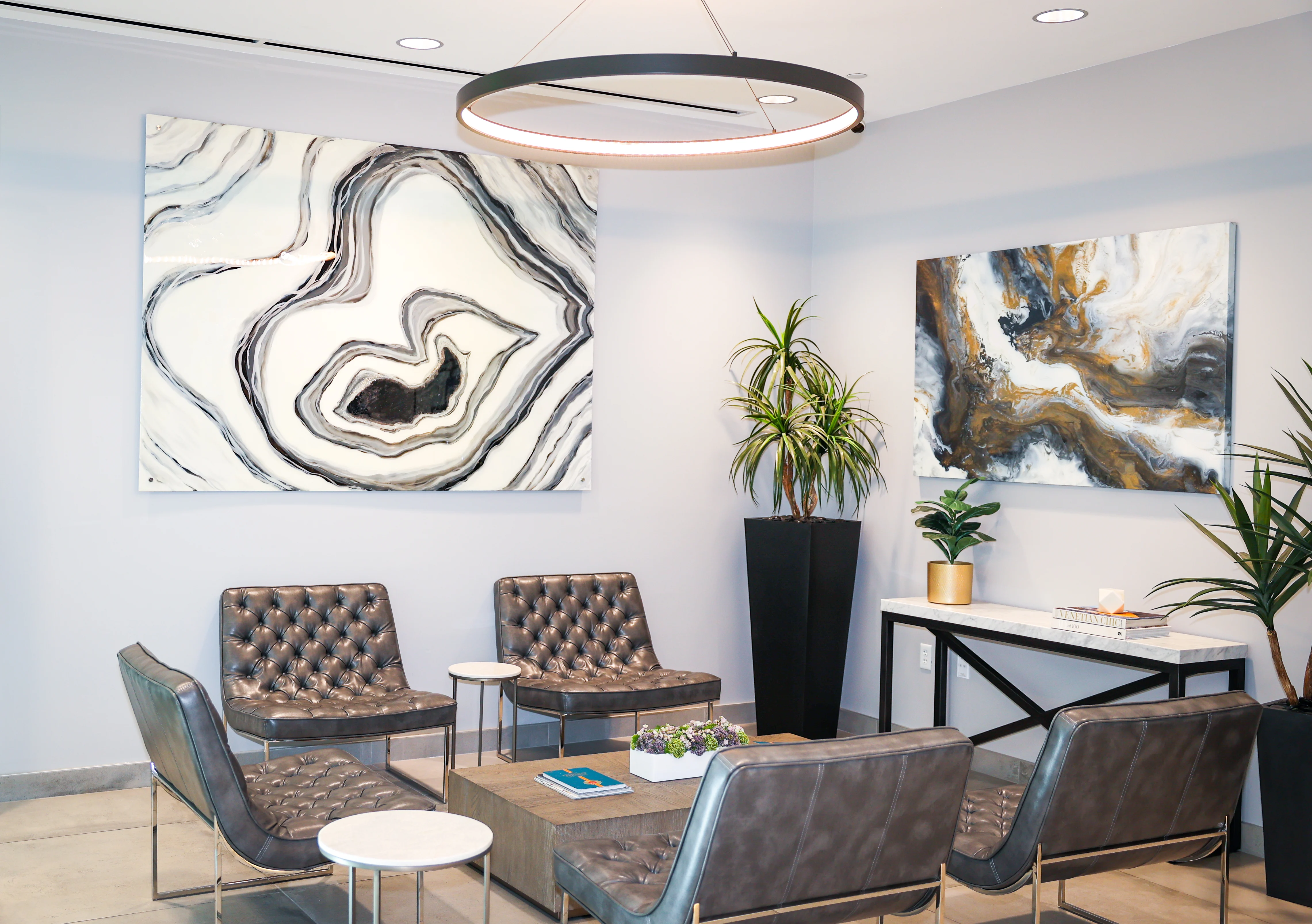 Waiting area with contemporary leather chairs, marble tables, and large modern art at Metropolitan Plastic Surgery Scottsdale office.