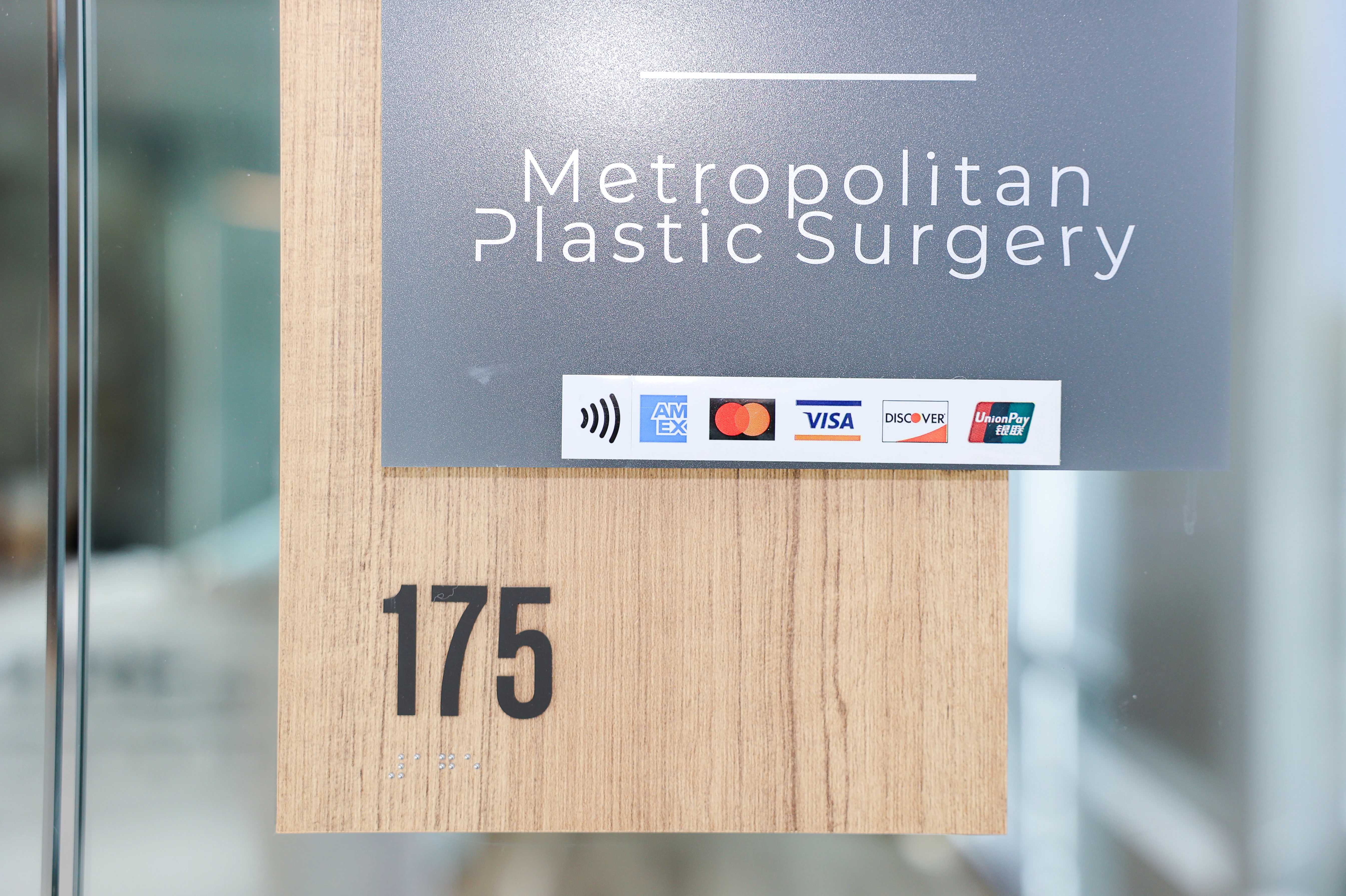 Exterior sign for Metropolitan Plastic Surgery suite 175 with credit card logos in Scottsdale, Arizona.
