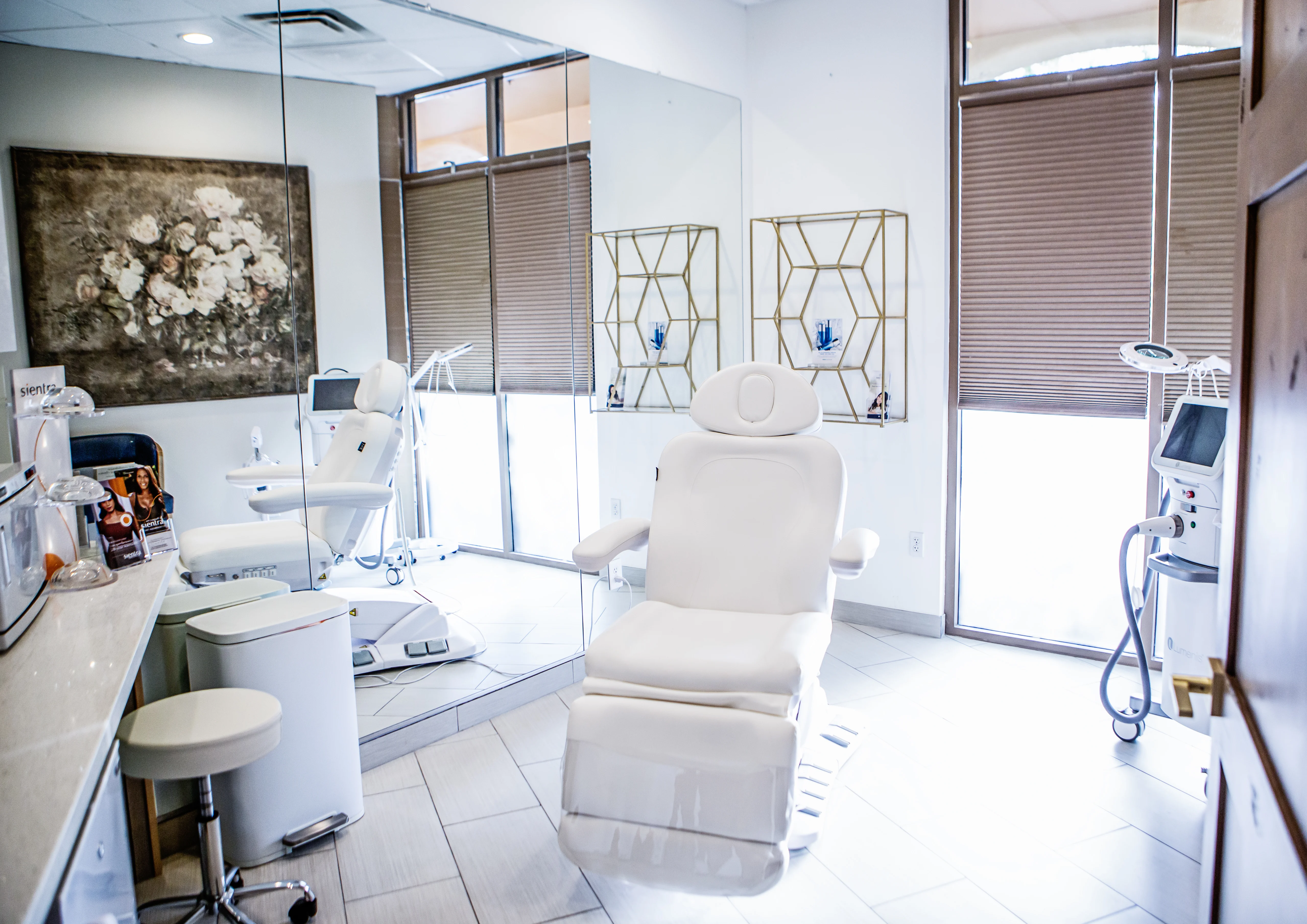 Carefree office treatment room with white reclining chair, large mirror, and laser equipment, designed for aesthetic consultations and treatments.